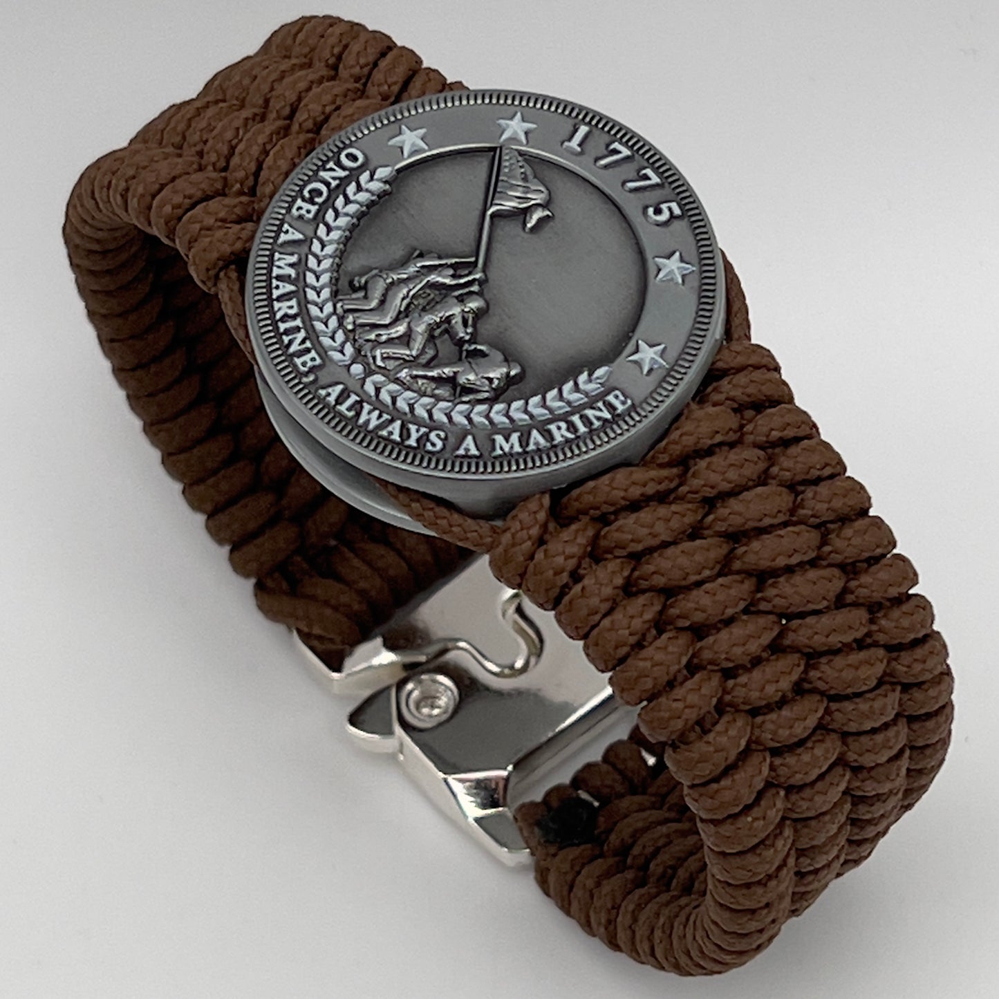 Thin, wide, flexible and comfortable braided United States Marine Corps Iwo Jima bracelet featuring an antique silver plated Iwo Jima flag raising medallion, a silver Cobra style tactical buckle and woven with Coyote Brown Type-1 paracord.