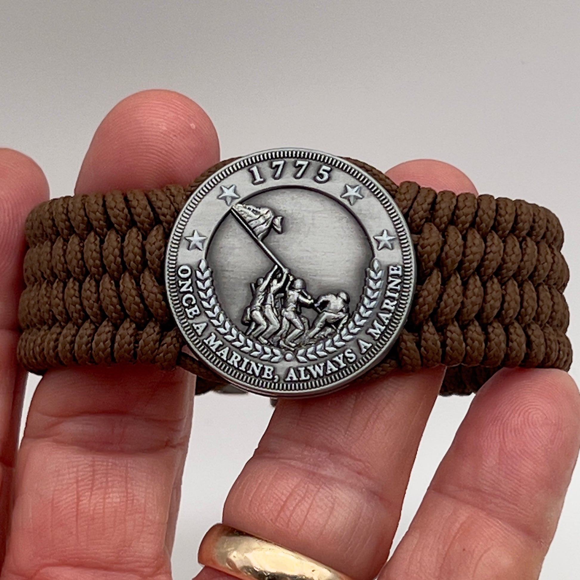 Thin, wide, flexible and comfortable braided United States Marine Corps Iwo Jima bracelet featuring an antique silver plated Iwo Jima flag raising medallion, a silver Cobra style tactical buckle and woven with Coyote Brown Type-1 paracord.