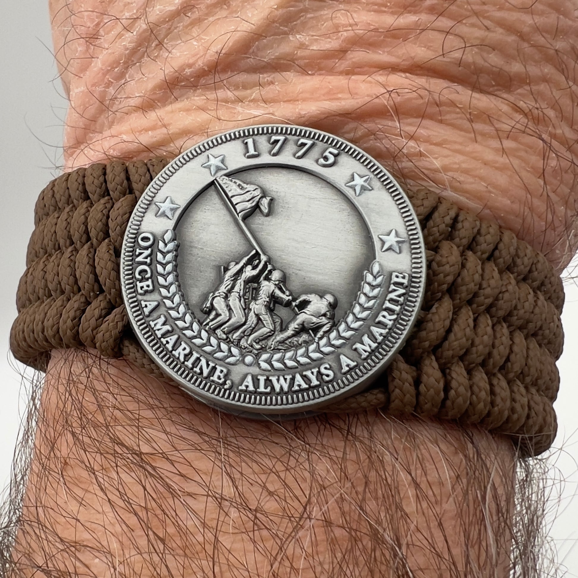 Thin, wide, flexible and comfortable braided United States Marine Corps Iwo Jima bracelet featuring an antique silver plated Iwo Jima flag raising medallion, a silver Cobra style tactical buckle and woven with Coyote Brown Type-1 paracord.