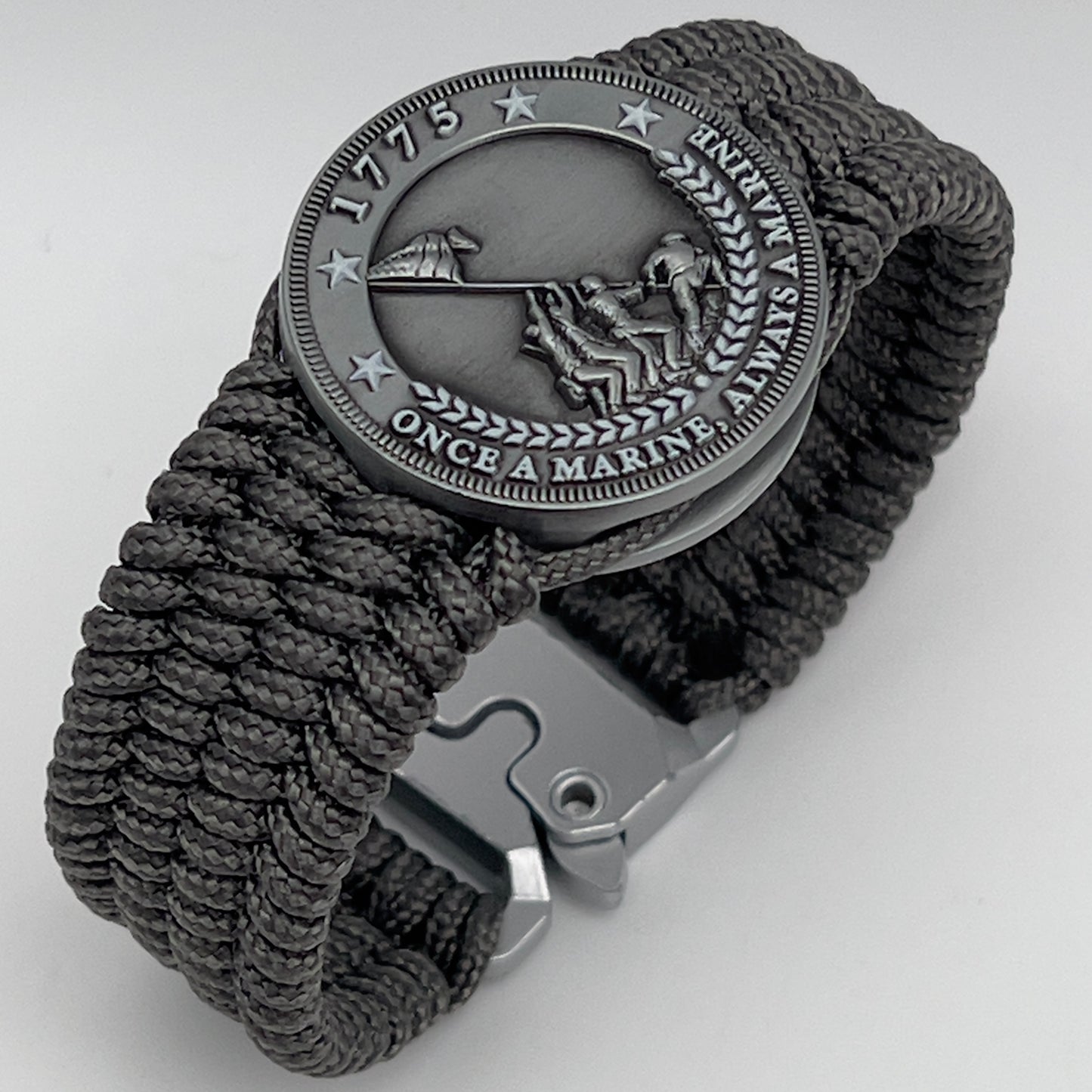 Thin, wide, flexible and comfortable braided United States Marine Corps Iwo Jima bracelet featuring an antique silver plated Iwo Jima flag raising medallion, a silver Cobra style tactical buckle and woven with gray Type-1 paracord.