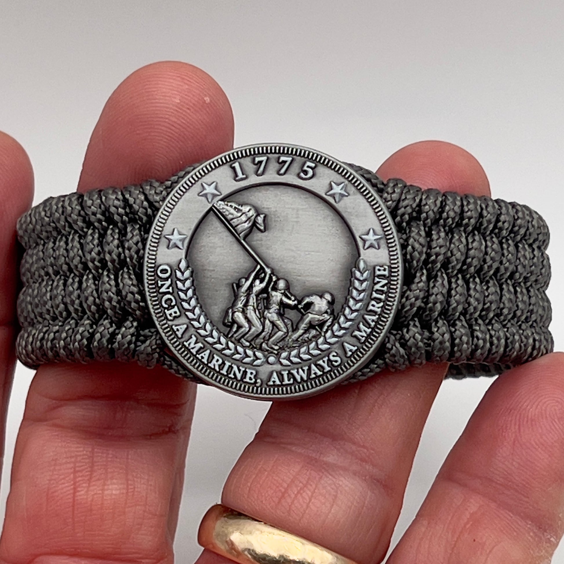 Thin, wide, flexible and comfortable braided United States Marine Corps Iwo Jima bracelet featuring an antique silver plated Iwo Jima flag raising medallion, a silver Cobra style tactical buckle and woven with gray Type-1 paracord.