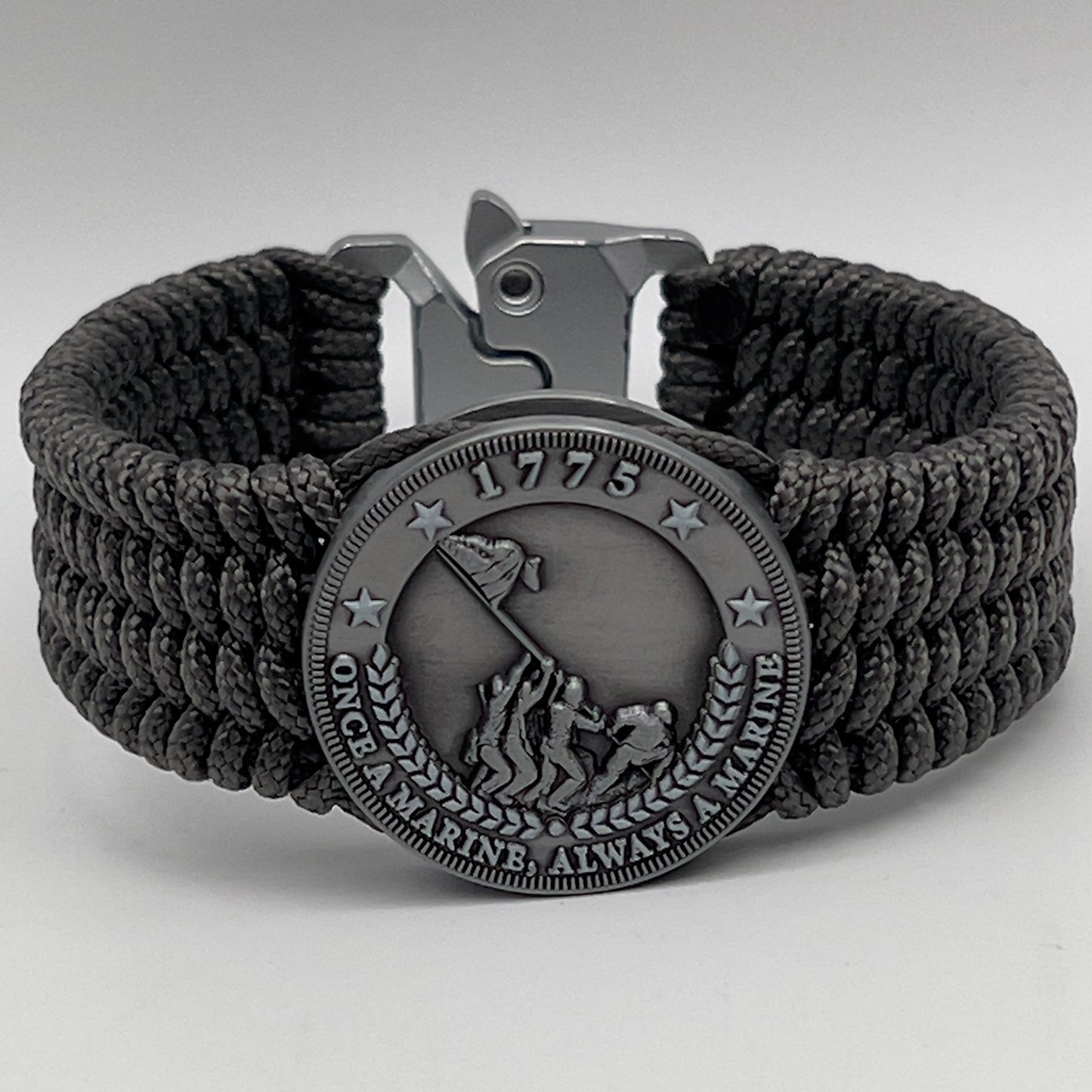 Thin, wide, flexible and comfortable braided United States Marine Corps Iwo Jima bracelet featuring an antique silver plated Iwo Jima flag raising medallion, a silver Cobra style tactical buckle and woven with gray Type-1 paracord.