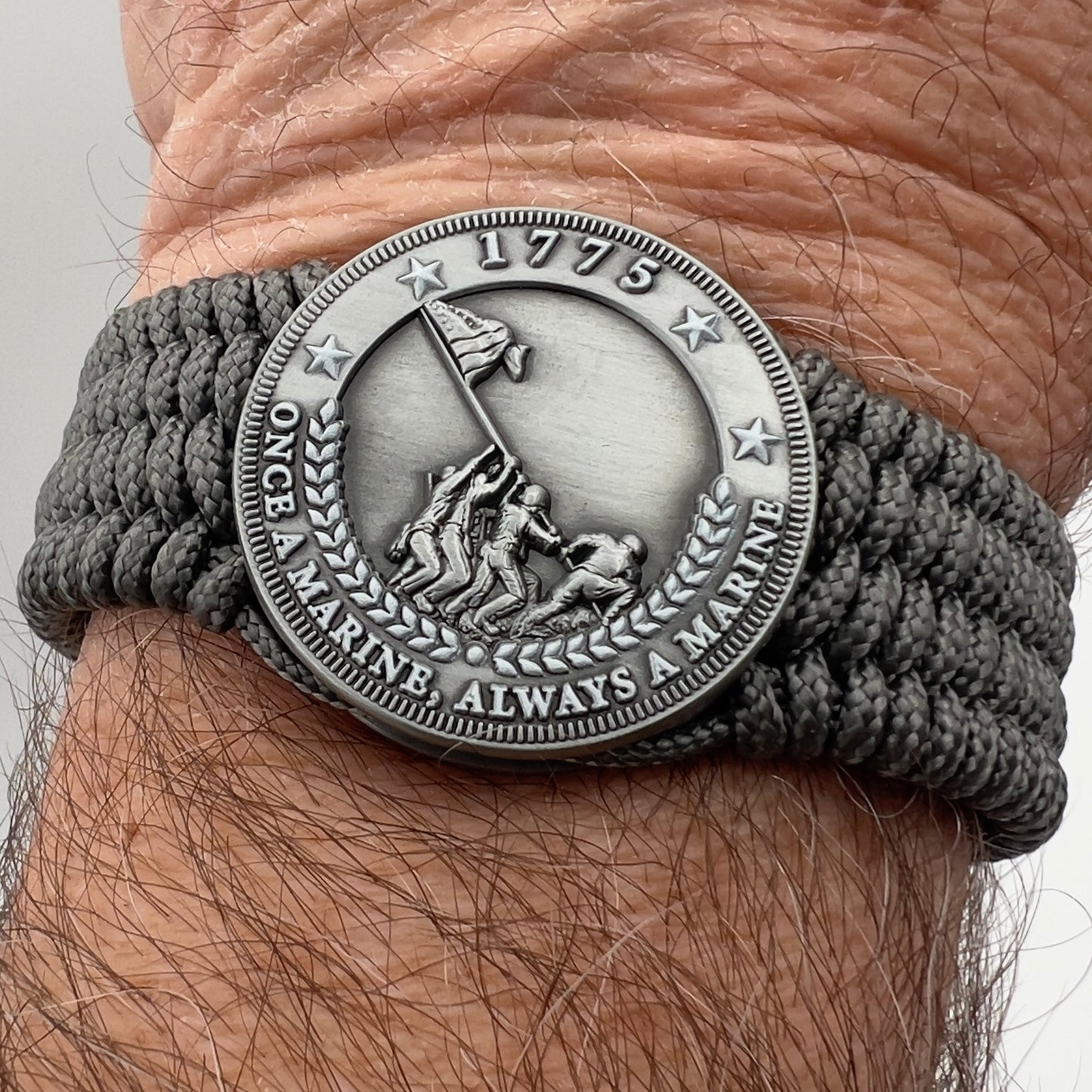 Thin, wide, flexible and comfortable braided United States Marine Corps Iwo Jima bracelet featuring an antique silver plated Iwo Jima flag raising medallion, a silver Cobra style tactical buckle and woven with gray Type-1 paracord.
