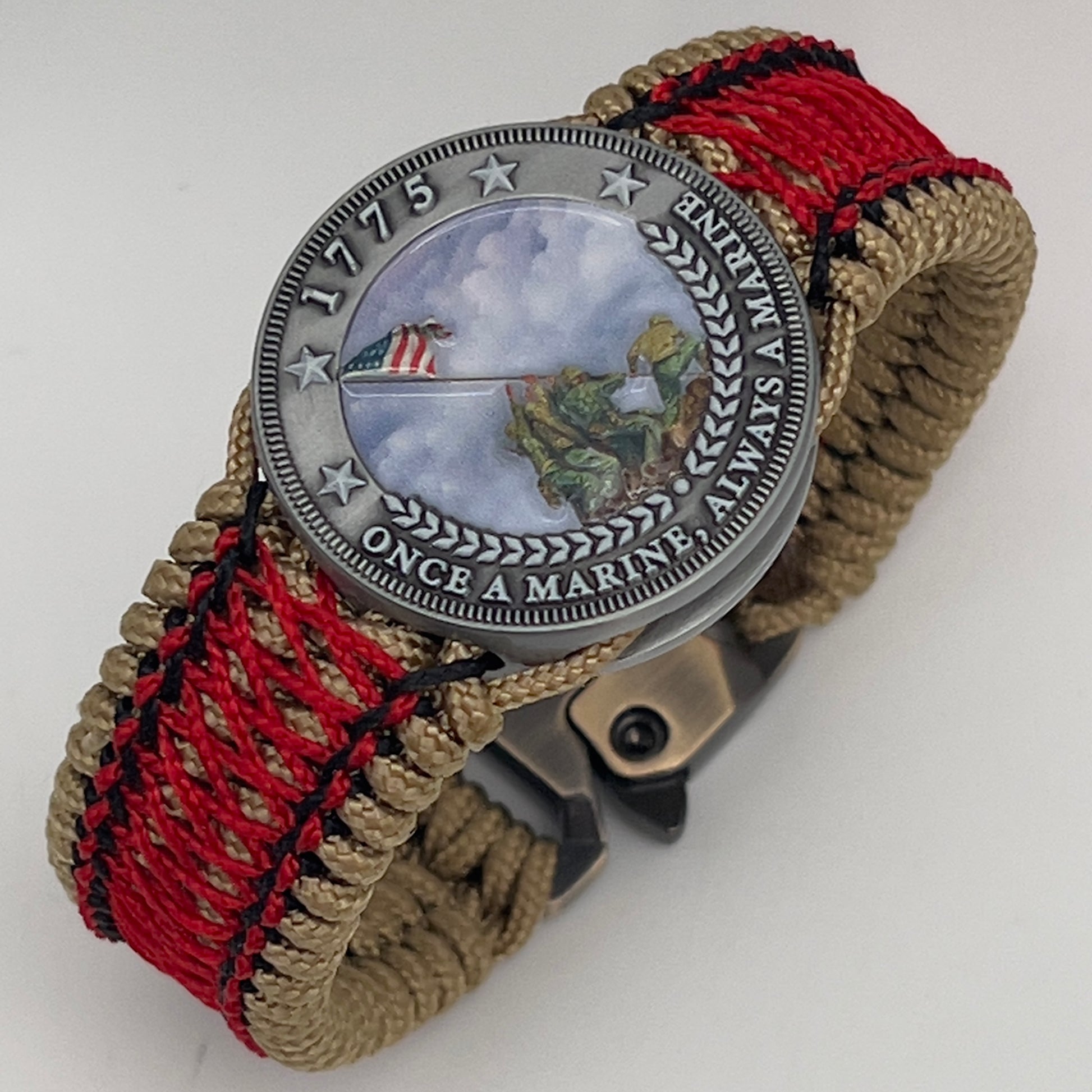 Thin, medium width, flexible and comfortable braided United States Marine Corps Iwo Jima bracelet featuring a UV painted antique silver plated Iwo Jima flag raising medallion, a gold Cobra style tactical buckle and woven with gold Type-1 paracord and Imperial Red and black nano cord.