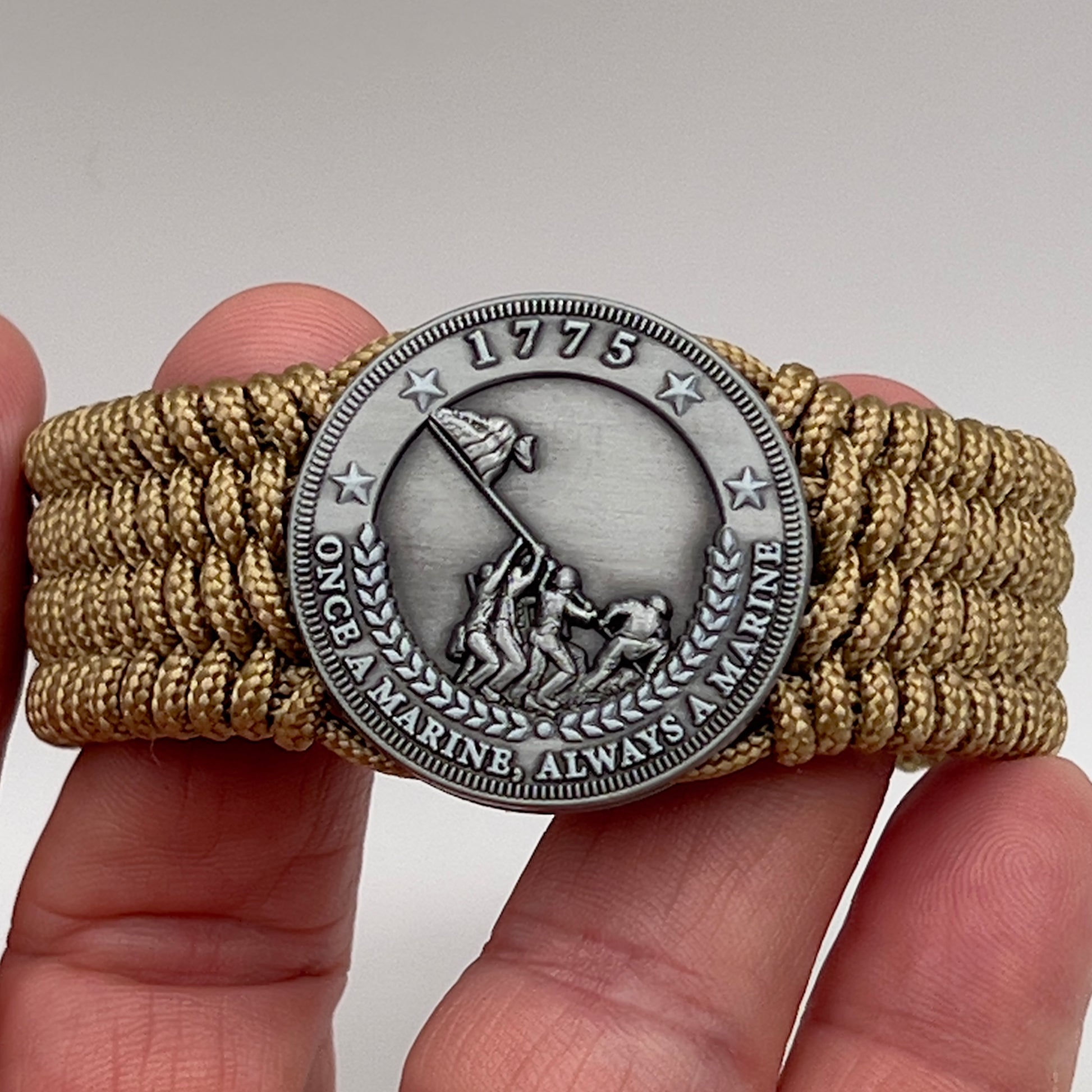 Thin, wide, flexible and comfortable braided United States Marine Corps Iwo Jima bracelet featuring an antique silver plated Iwo Jima flag raising medallion, a gold Cobra style tactical buckle and woven with gold Type-1 paracord.