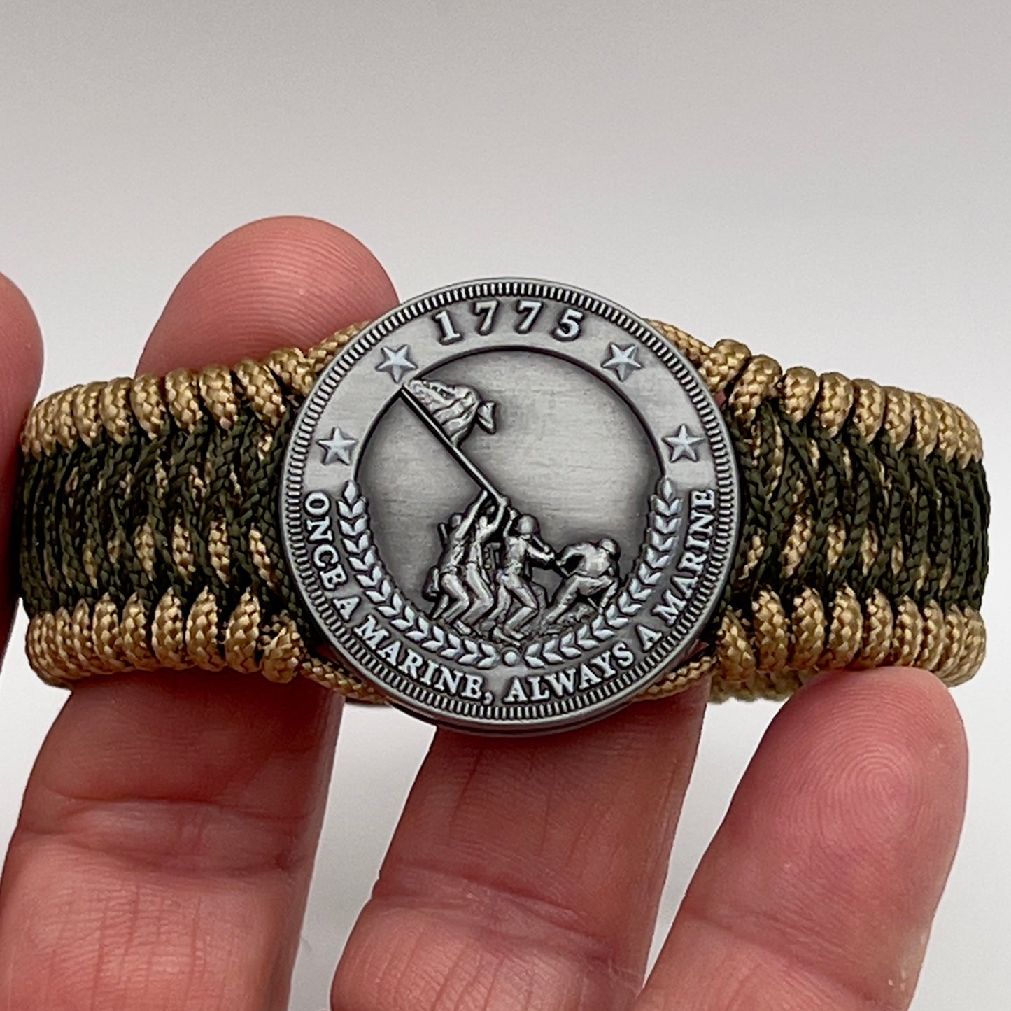 Thin, wide, flexible and comfortable braided United States Marine Corps Iwo Jima bracelet featuring an antique silver plated Iwo Jima flag raising medallion, a gold Cobra style tactical buckle and woven with gold Type-1 paracord and Olive Drab nano cord.