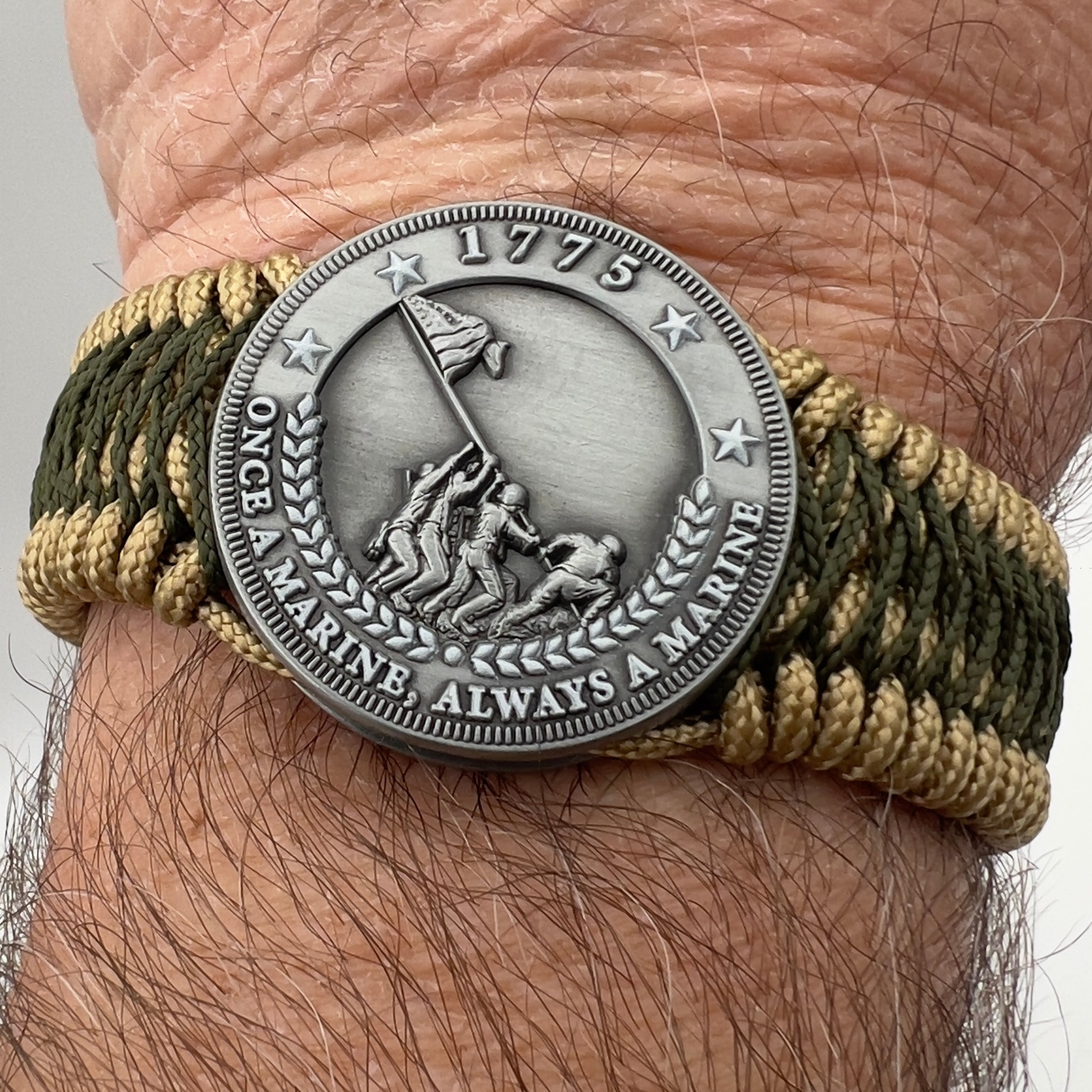 Thin, wide, flexible and comfortable braided United States Marine Corps Iwo Jima bracelet featuring an antique silver plated Iwo Jima flag raising medallion, a gold Cobra style tactical buckle and woven with gold Type-1 paracord and Olive Drab nano cord.