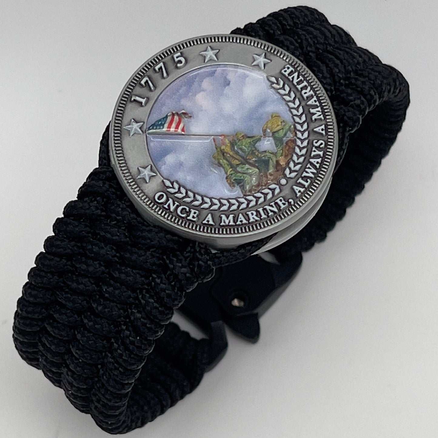 Thin, wide, flexible and comfortable braided United States Marine Corps Iwo Jima bracelet featuring an antique silver plated UV painted Iwo Jima flag raising medallion, a black Cobra style tactical buckle and woven with black Type-1 paracord.