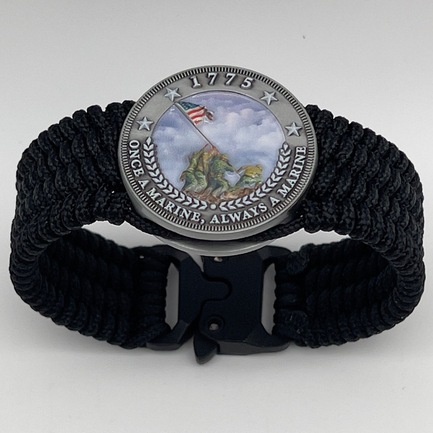 Thin, wide, flexible and comfortable braided United States Marine Corps Iwo Jima bracelet featuring an antique silver plated UV painted Iwo Jima flag raising medallion, a black Cobra style tactical buckle and woven with black Type-1 paracord.