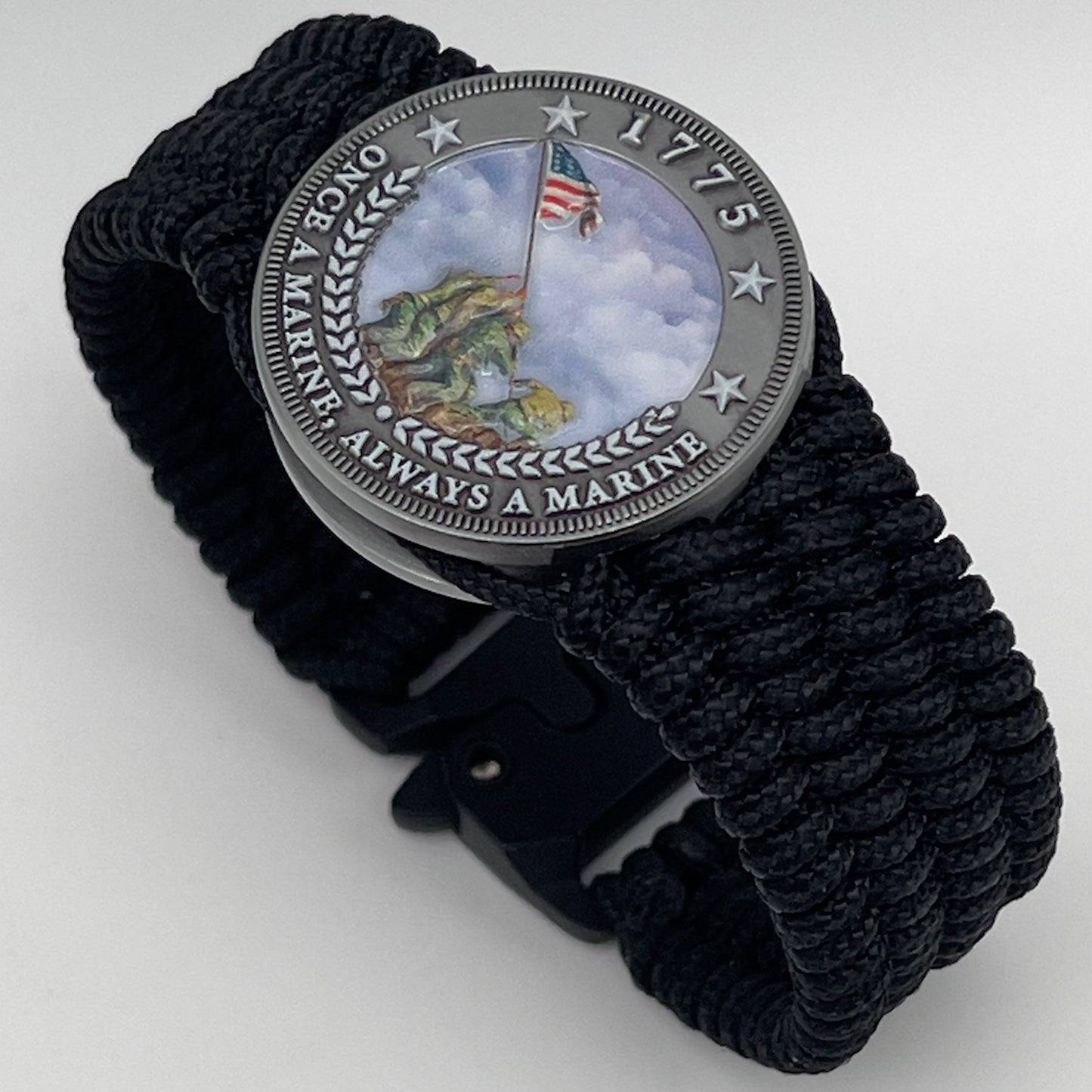 Thin, wide, flexible and comfortable braided United States Marine Corps Iwo Jima bracelet featuring an antique silver plated UV painted Iwo Jima flag raising medallion, a black Cobra style tactical buckle and woven with black Type-1 paracord.