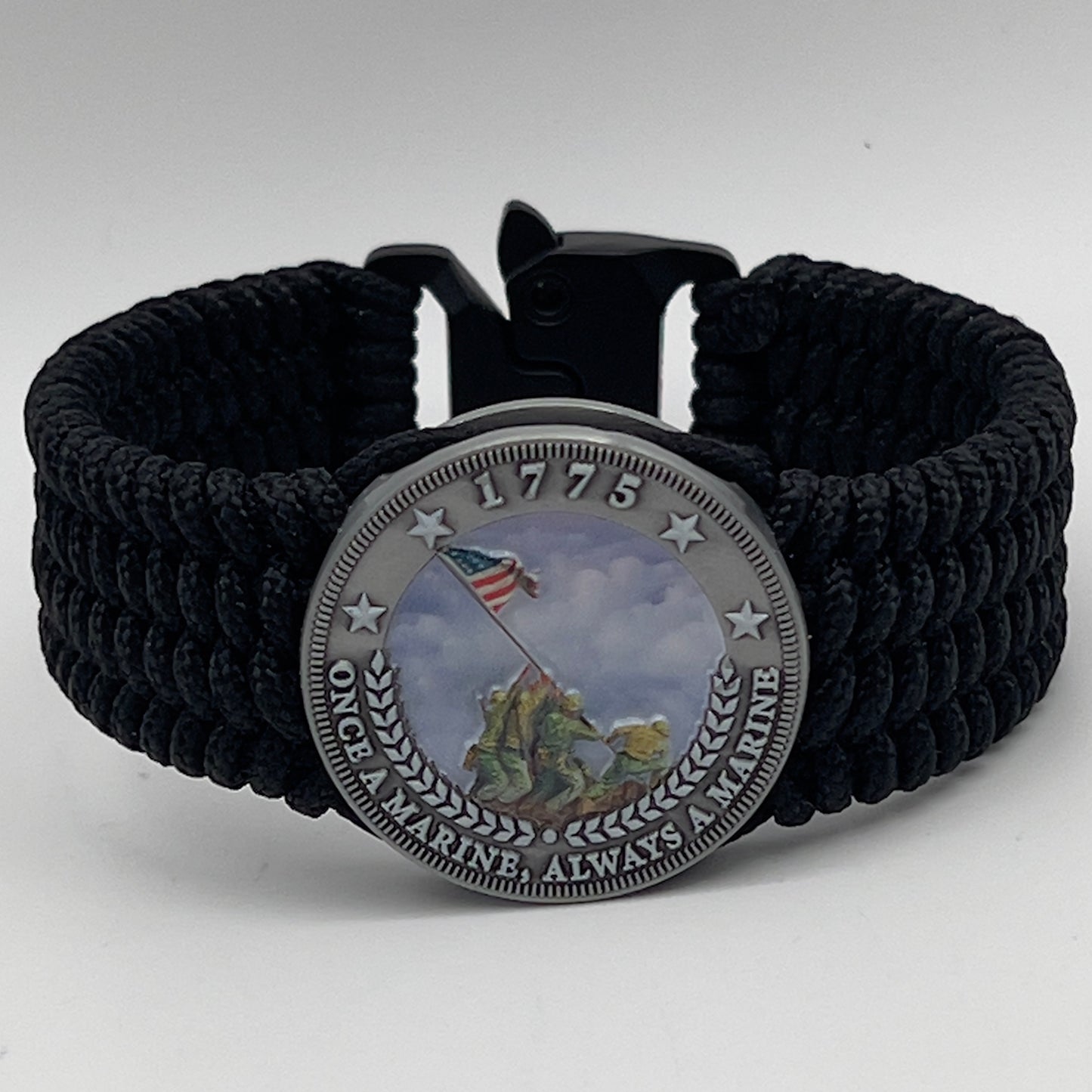Thin, wide, flexible and comfortable braided United States Marine Corps Iwo Jima bracelet featuring an antique silver plated UV painted Iwo Jima flag raising medallion, a black Cobra style tactical buckle and woven with black Type-1 paracord.