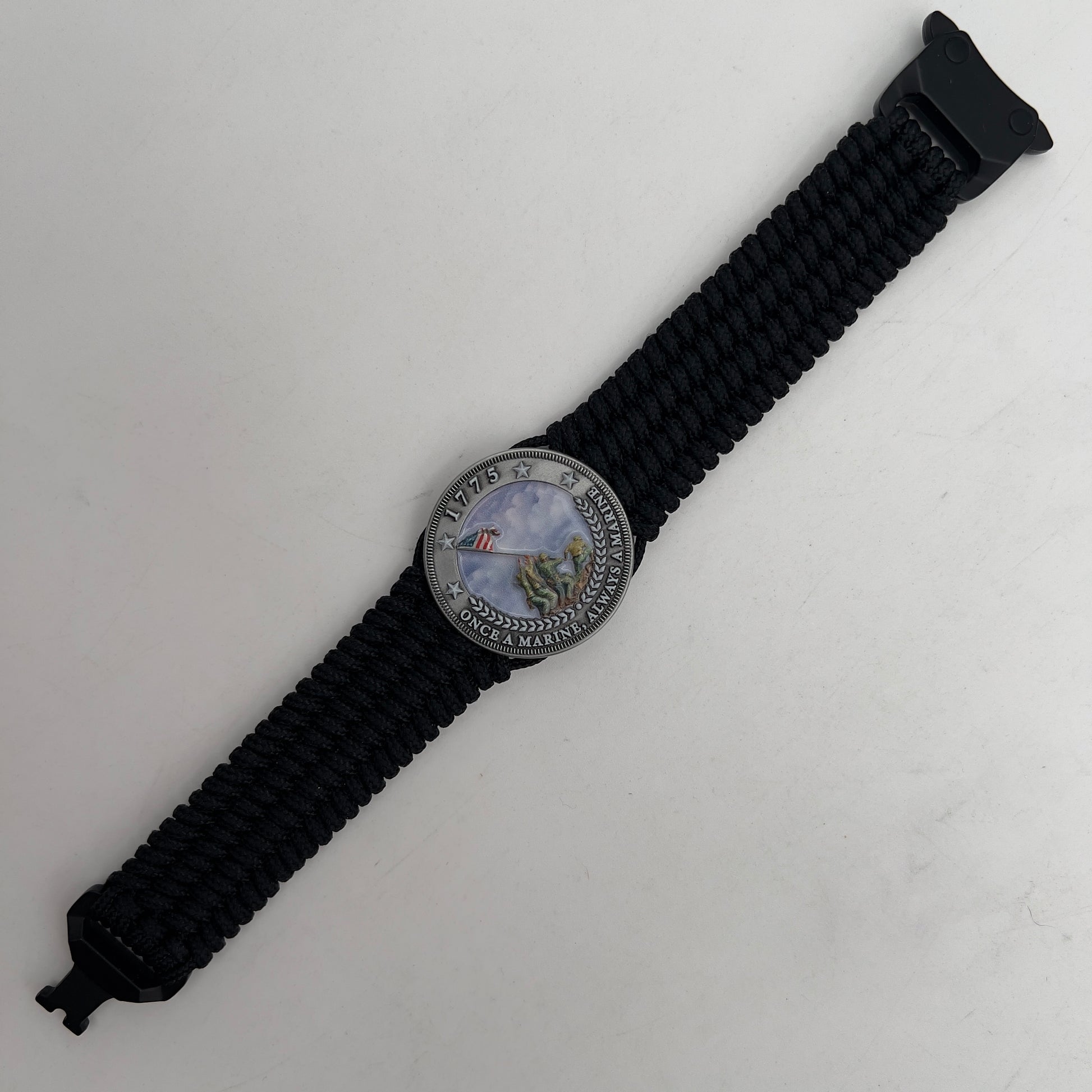 Thin, wide, flexible and comfortable braided United States Marine Corps Iwo Jima bracelet featuring an antique silver plated UV painted Iwo Jima flag raising medallion, a black Cobra style tactical buckle and woven with black Type-1 paracord.