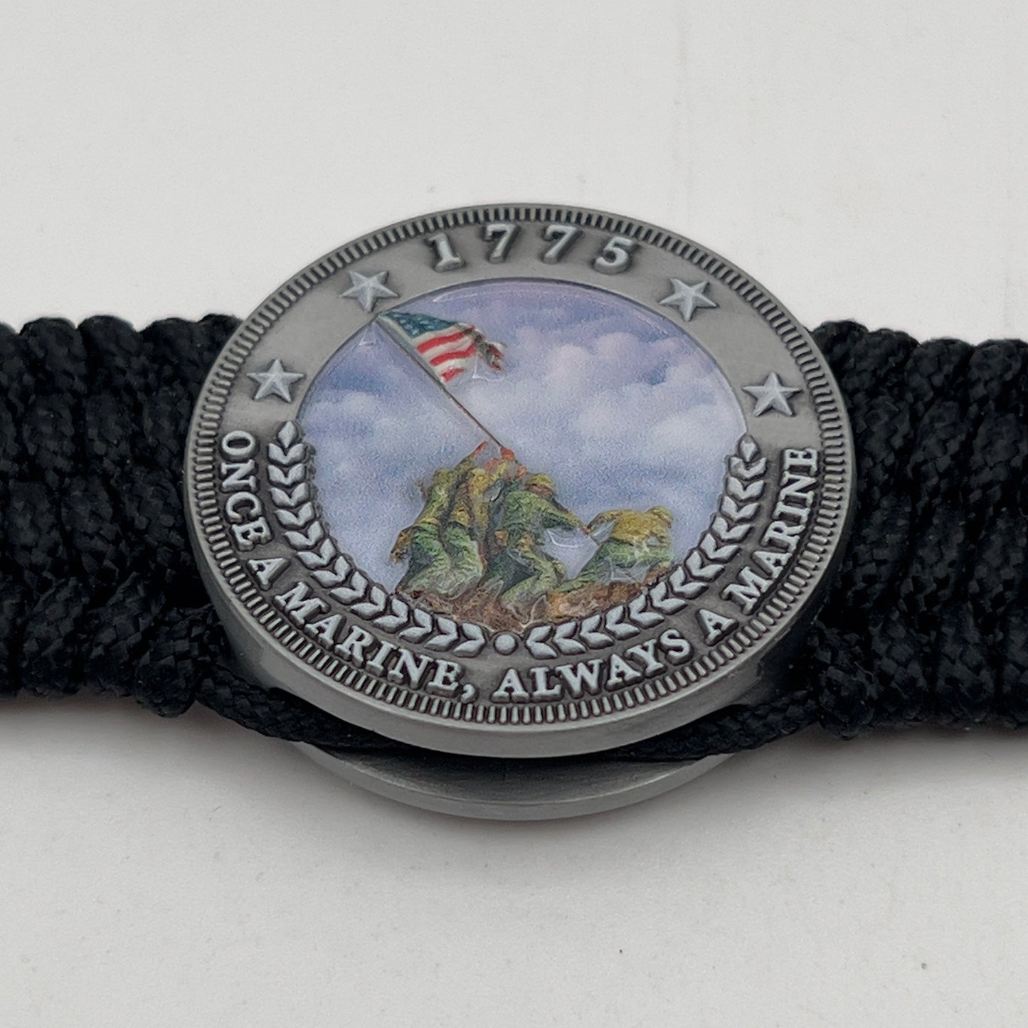 Thin, wide, flexible and comfortable braided United States Marine Corps Iwo Jima bracelet featuring an antique silver plated UV painted Iwo Jima flag raising medallion, a black Cobra style tactical buckle and woven with black Type-1 paracord.