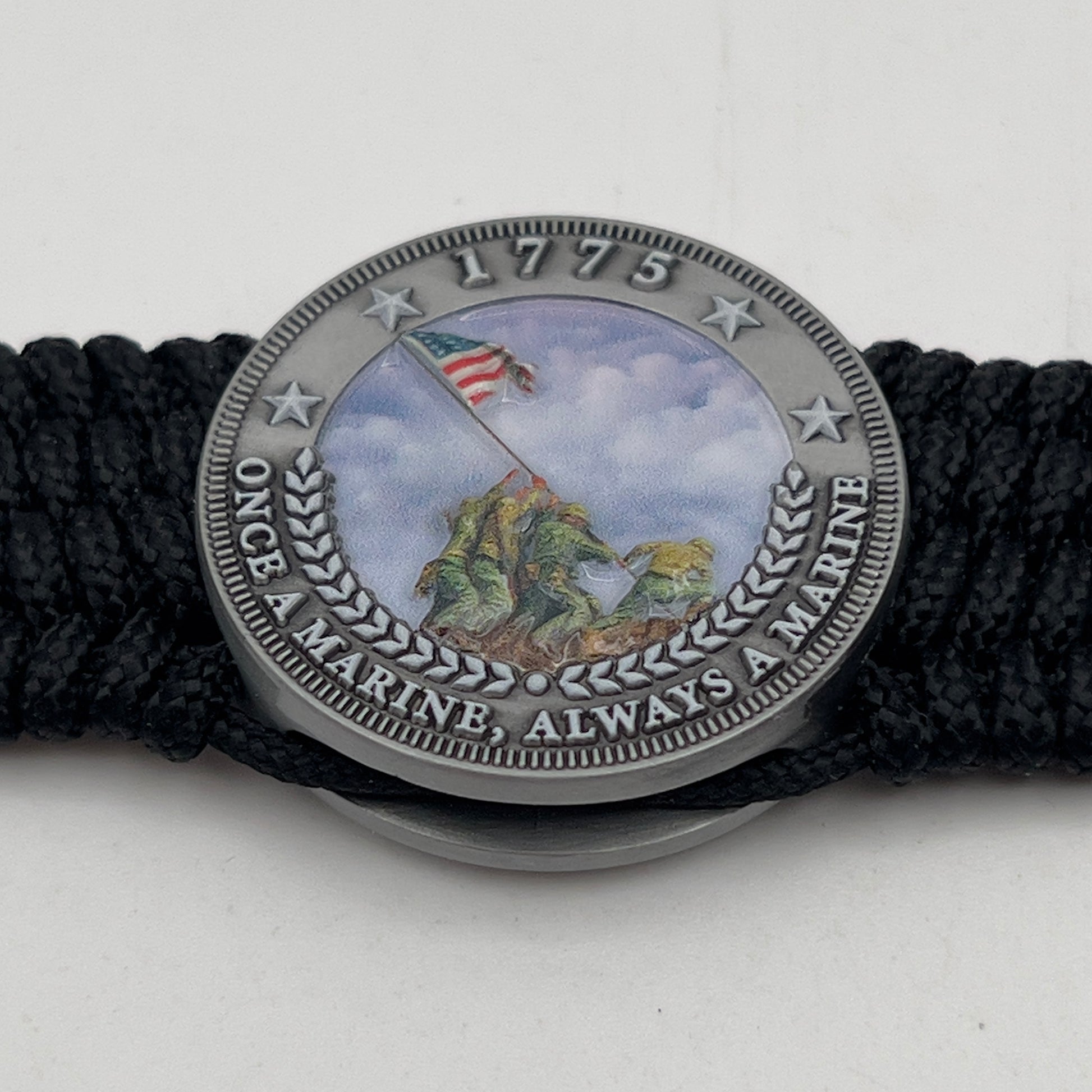 Thin, wide, flexible and comfortable braided United States Marine Corps Iwo Jima bracelet featuring an antique silver plated UV painted Iwo Jima flag raising medallion, a black Cobra style tactical buckle and woven with black Type-1 paracord.