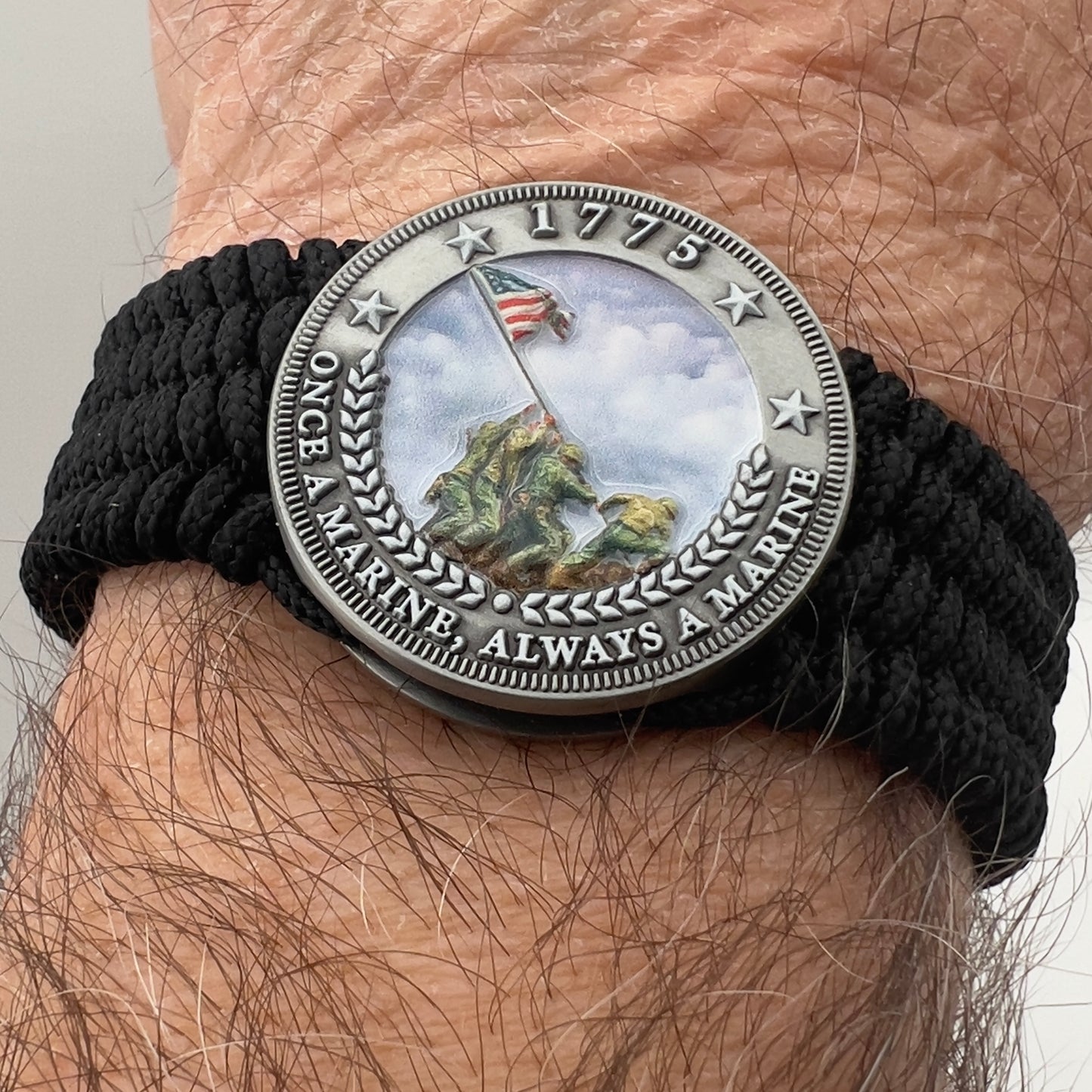 Thin, wide, flexible and comfortable braided United States Marine Corps Iwo Jima bracelet featuring an antique silver plated UV painted Iwo Jima flag raising medallion, a black Cobra style tactical buckle and woven with black Type-1 paracord.