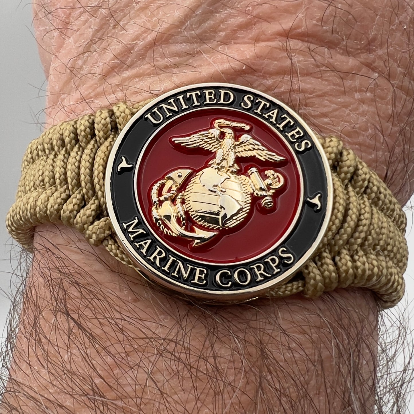 Thick, narrow, flexible and comfortable braided United States Marine Corps bracelet featuring a 24K gold plated USMC officer Eagle Globe and Anchor medallion, a gold Cobra style tactical buckle and woven with gold Type-1 paracord.