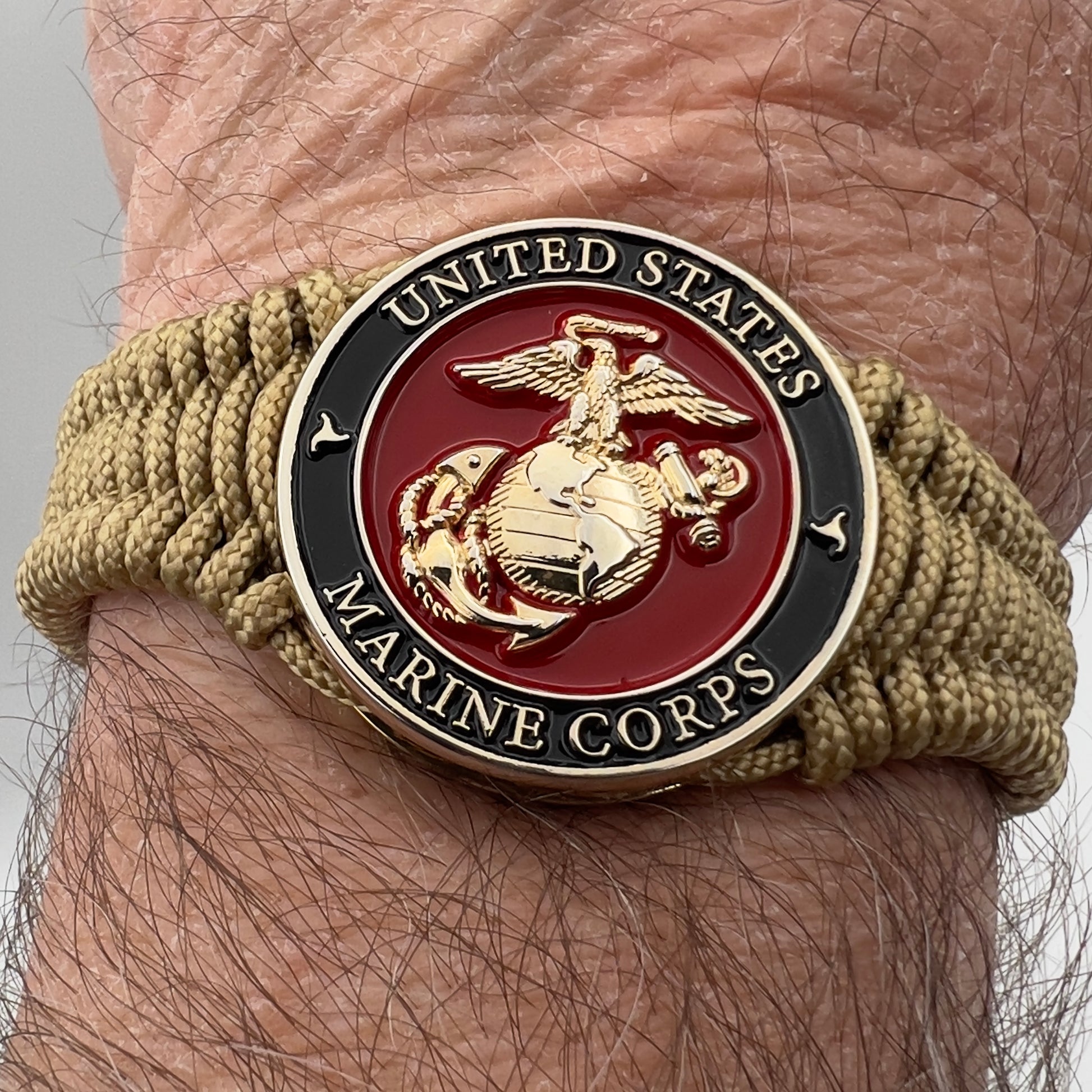 Thick, narrow, flexible and comfortable braided United States Marine Corps bracelet featuring a 24K gold plated USMC officer Eagle Globe and Anchor medallion, a gold Cobra style tactical buckle and woven with gold Type-1 paracord.