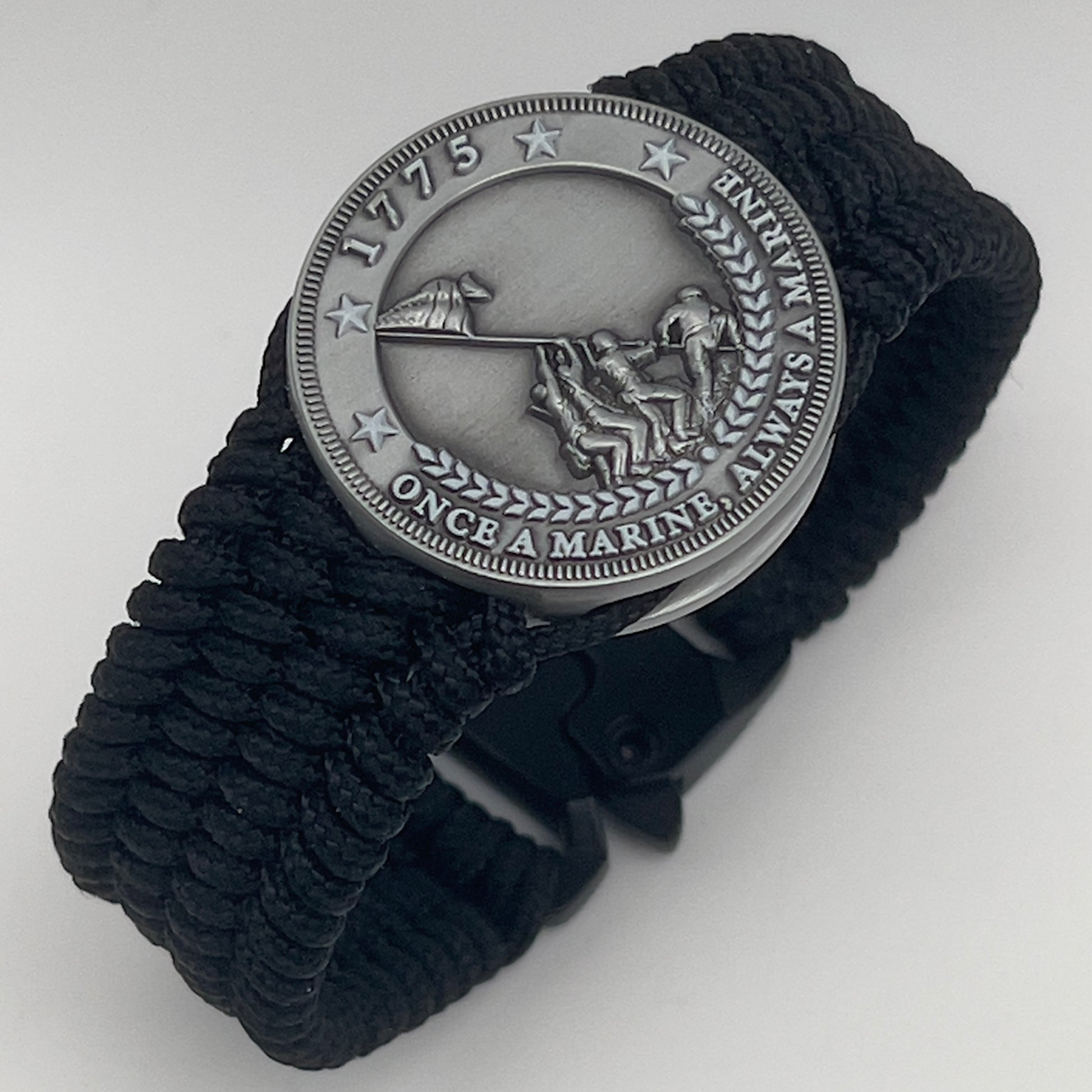 Thin, wide, flexible and comfortable braided United States Marine Corps Iwo Jima bracelet featuring an antique silver plated Iwo Jima flag raising medallion, a black Cobra style tactical buckle and woven with black Type-1 paracord.