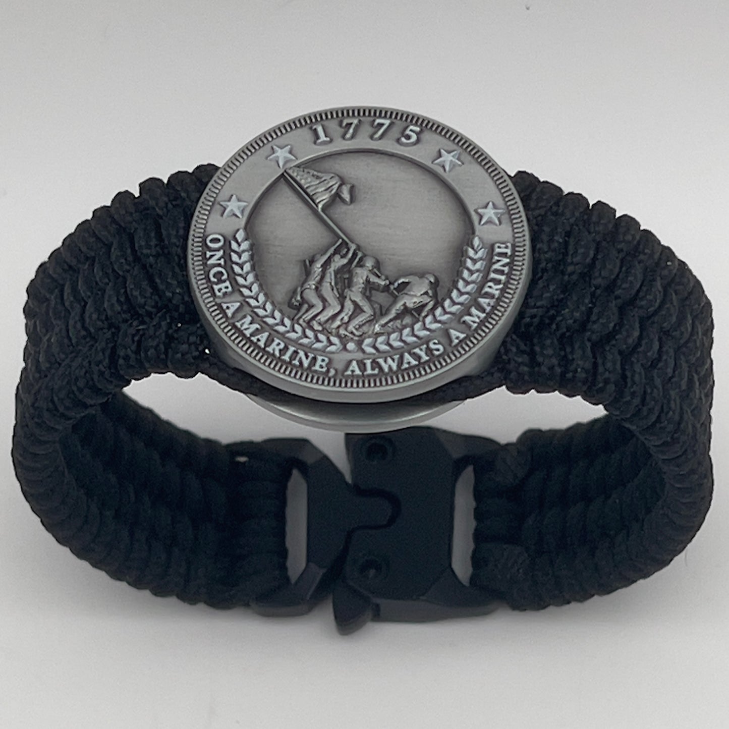Thin, wide, flexible and comfortable braided United States Marine Corps Iwo Jima bracelet featuring an antique silver plated Iwo Jima flag raising medallion, a black Cobra style tactical buckle and woven with black Type-1 paracord.