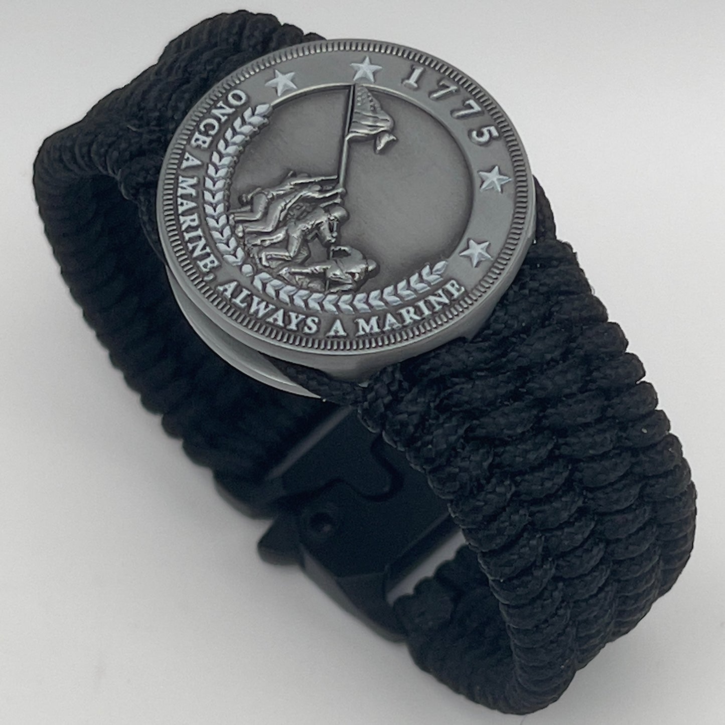 Thin, wide, flexible and comfortable braided United States Marine Corps Iwo Jima bracelet featuring an antique silver plated Iwo Jima flag raising medallion, a black Cobra style tactical buckle and woven with black Type-1 paracord.