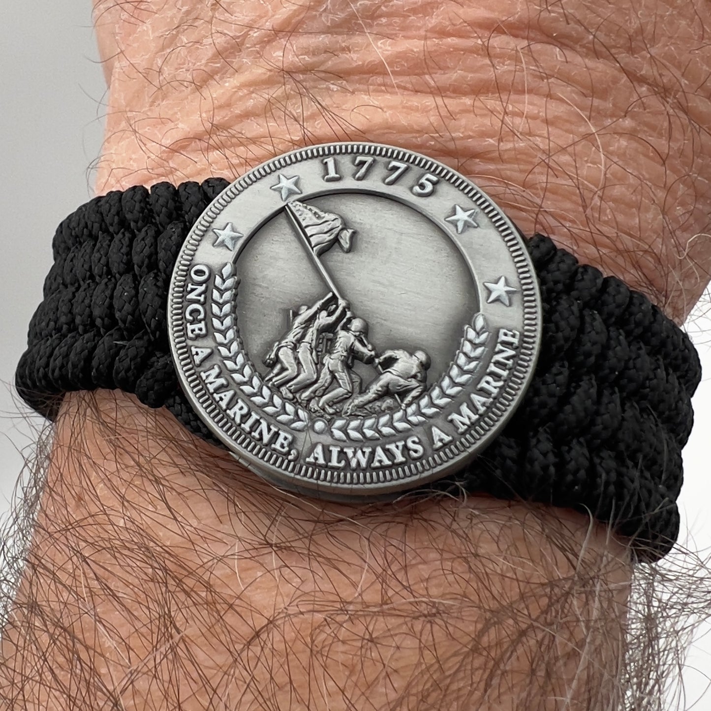 Thin, wide, flexible and comfortable braided United States Marine Corps Iwo Jima bracelet featuring an antique silver plated Iwo Jima flag raising medallion, a black Cobra style tactical buckle and woven with black Type-1 paracord.