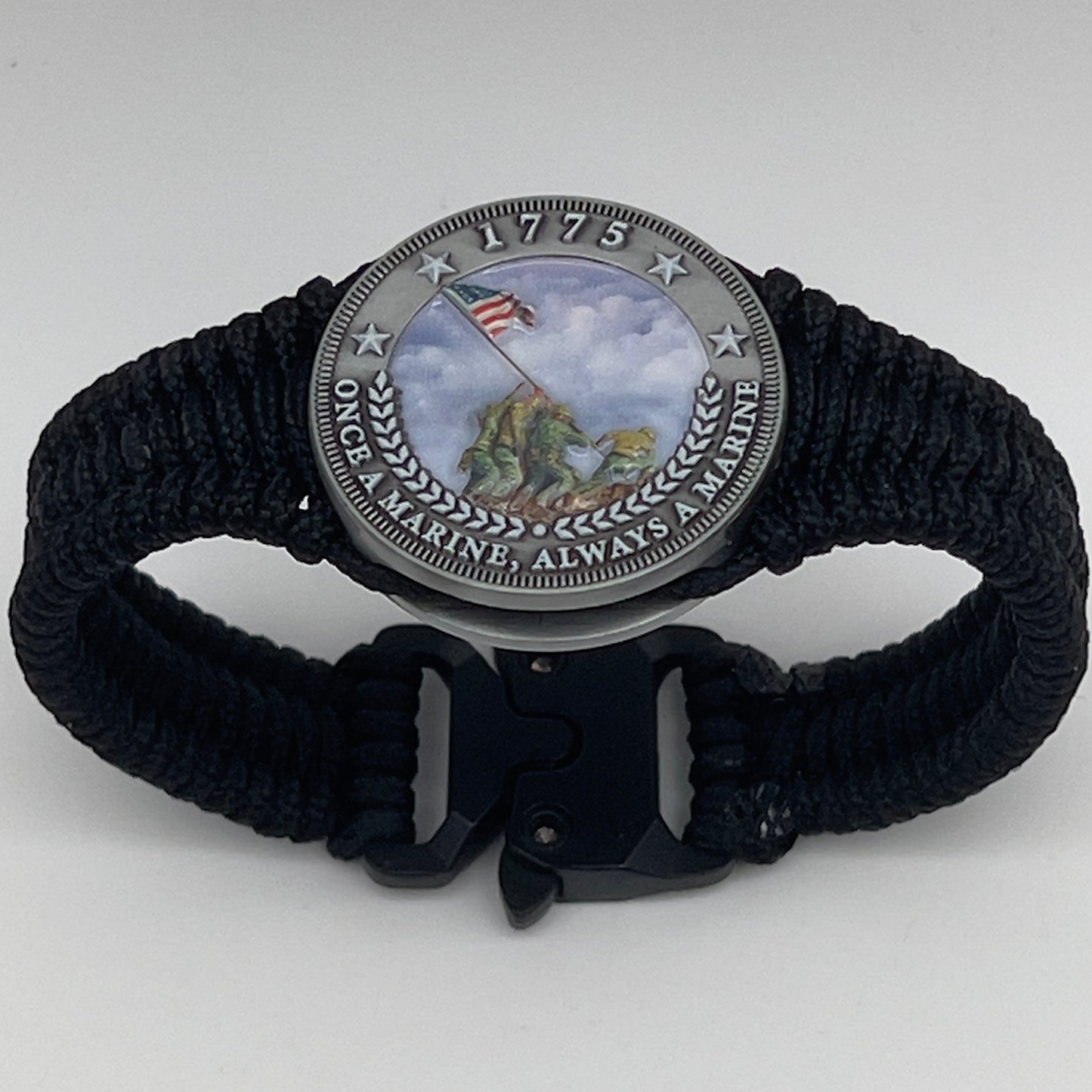 Thin, narrow and comfortable braided United States Marine Corps Iwo Jima bracelet featuring an antique silver plated UV painted Iwo Jima flag raising medallion, a black Cobra style tactical buckle and woven with black type-1 paracord.