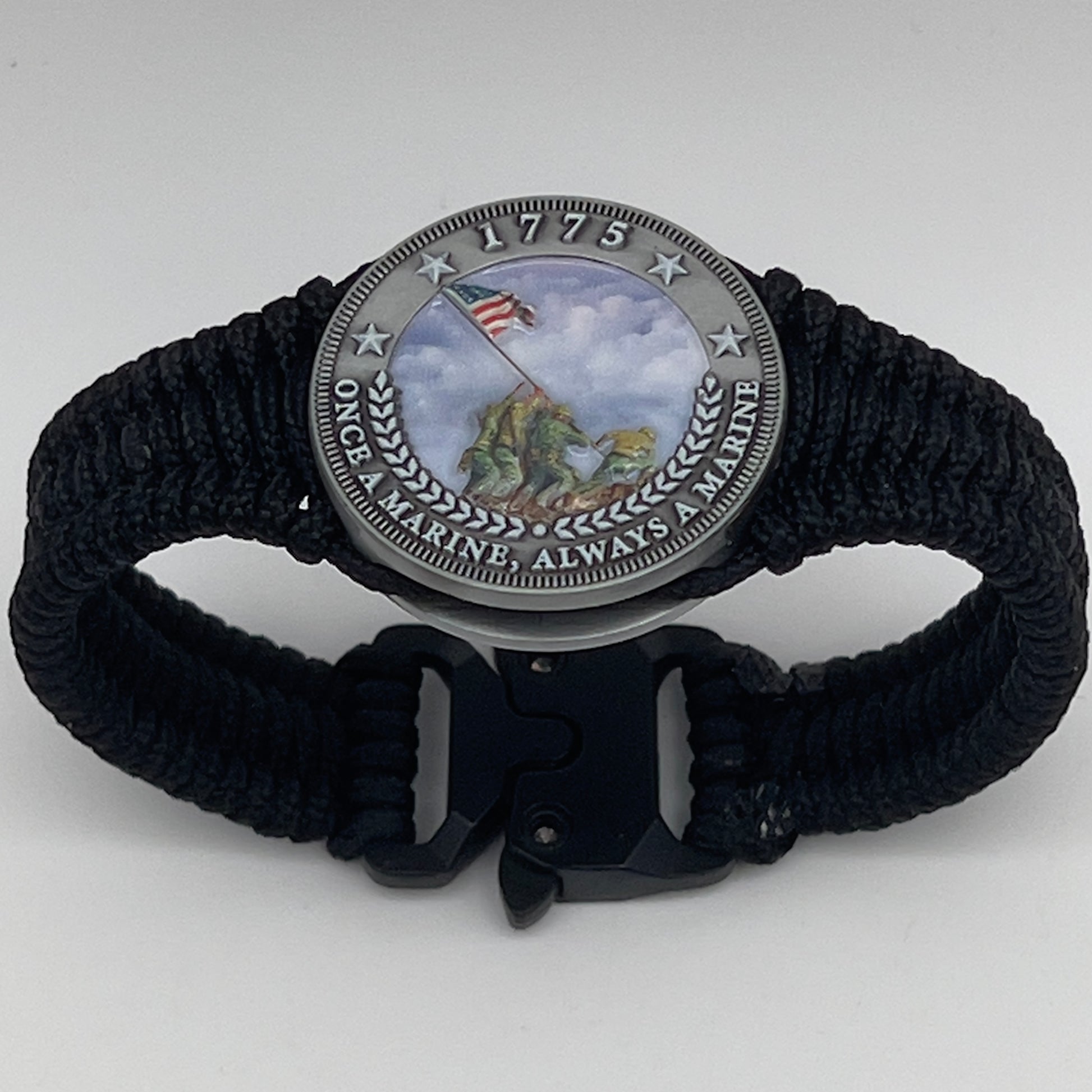 Thin, narrow and comfortable braided United States Marine Corps Iwo Jima bracelet featuring an antique silver plated UV painted Iwo Jima flag raising medallion, a black Cobra style tactical buckle and woven with black type-1 paracord.