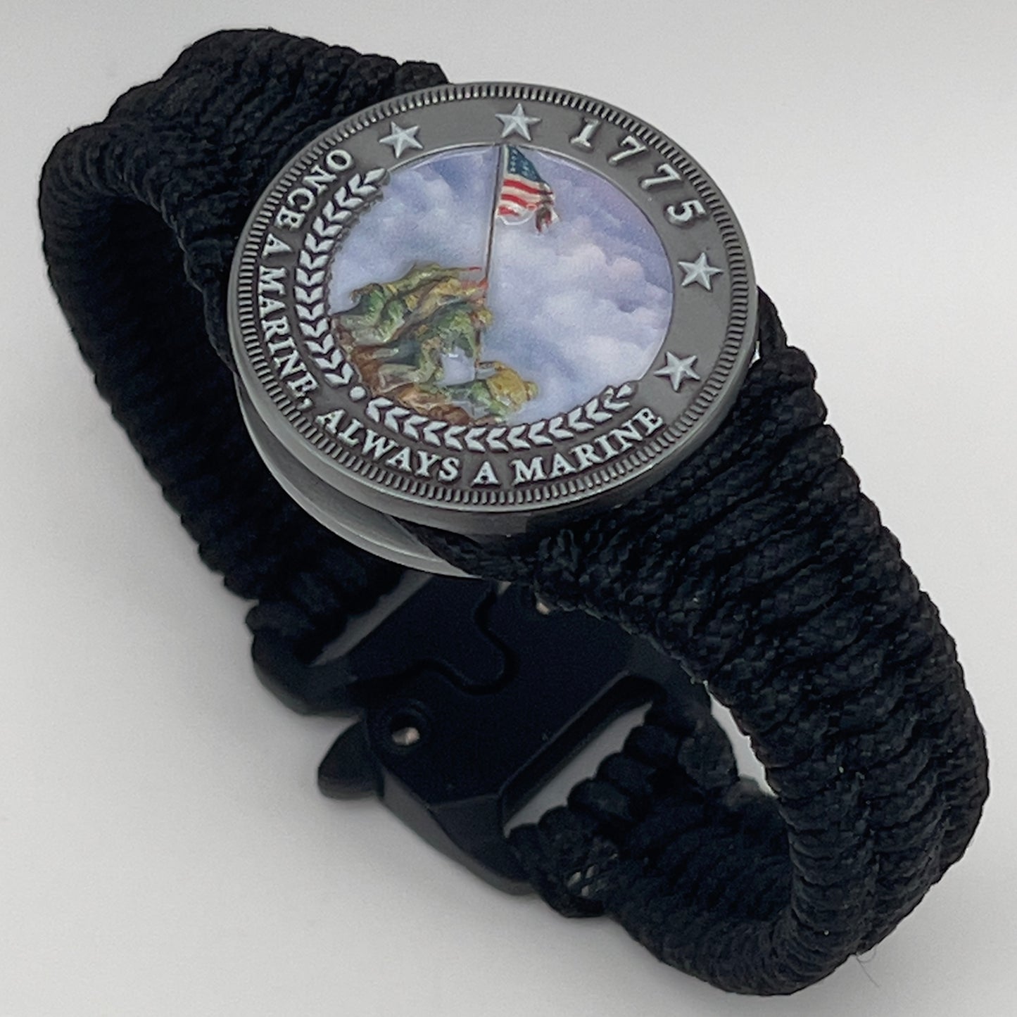 Thin, narrow and comfortable braided United States Marine Corps Iwo Jima bracelet featuring an antique silver plated UV painted Iwo Jima flag raising medallion, a black Cobra style tactical buckle and woven with black type-1 paracord.