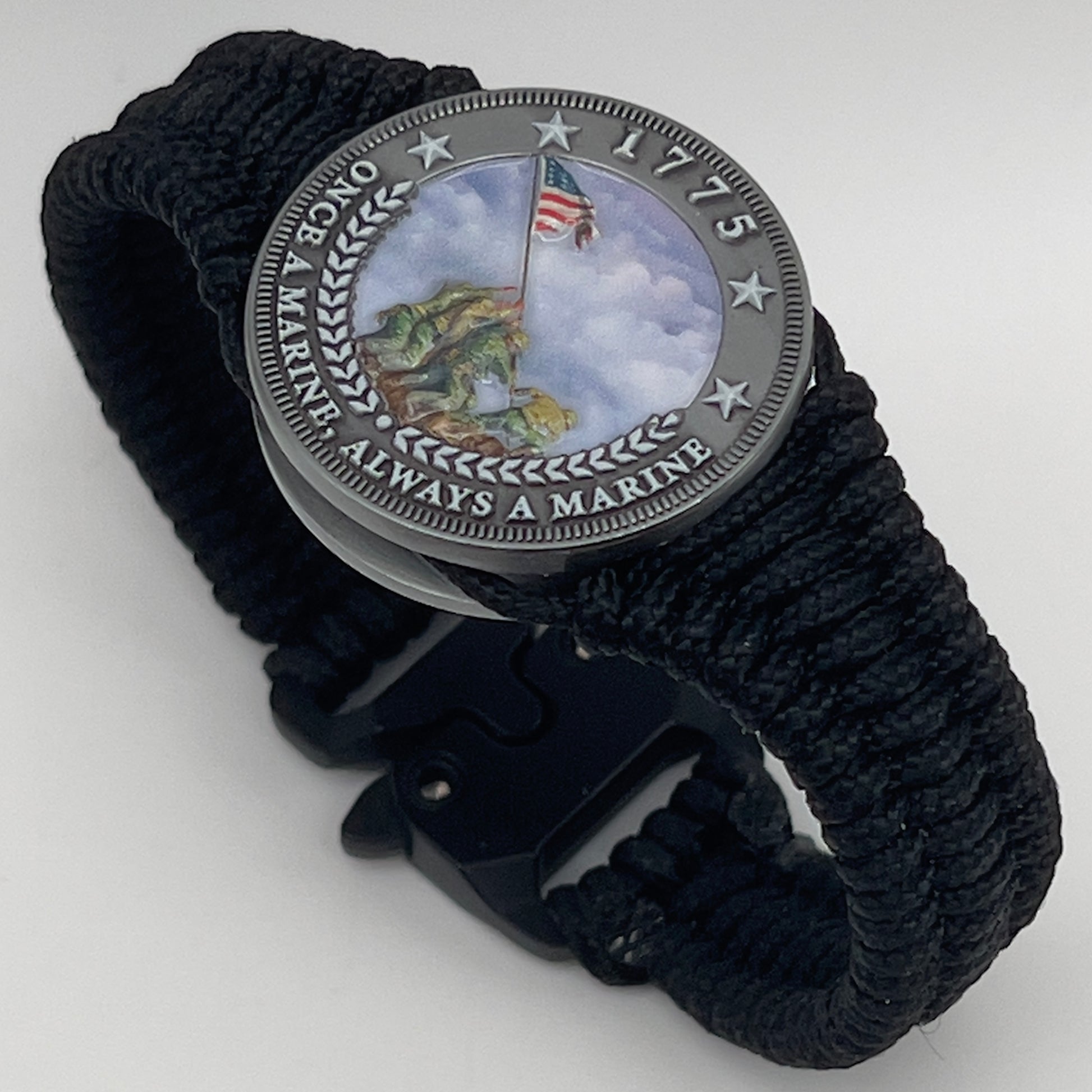 Thin, narrow and comfortable braided United States Marine Corps Iwo Jima bracelet featuring an antique silver plated UV painted Iwo Jima flag raising medallion, a black Cobra style tactical buckle and woven with black type-1 paracord.