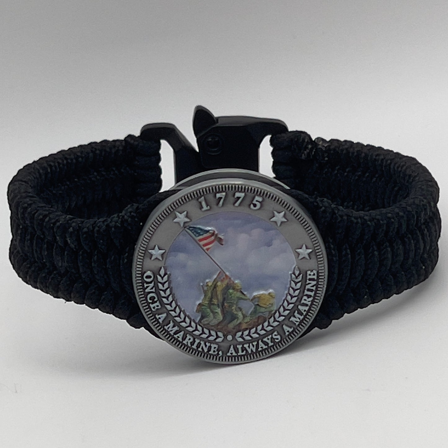 Thin, narrow and comfortable braided United States Marine Corps Iwo Jima bracelet featuring an antique silver plated UV painted Iwo Jima flag raising medallion, a black Cobra style tactical buckle and woven with black type-1 paracord.
