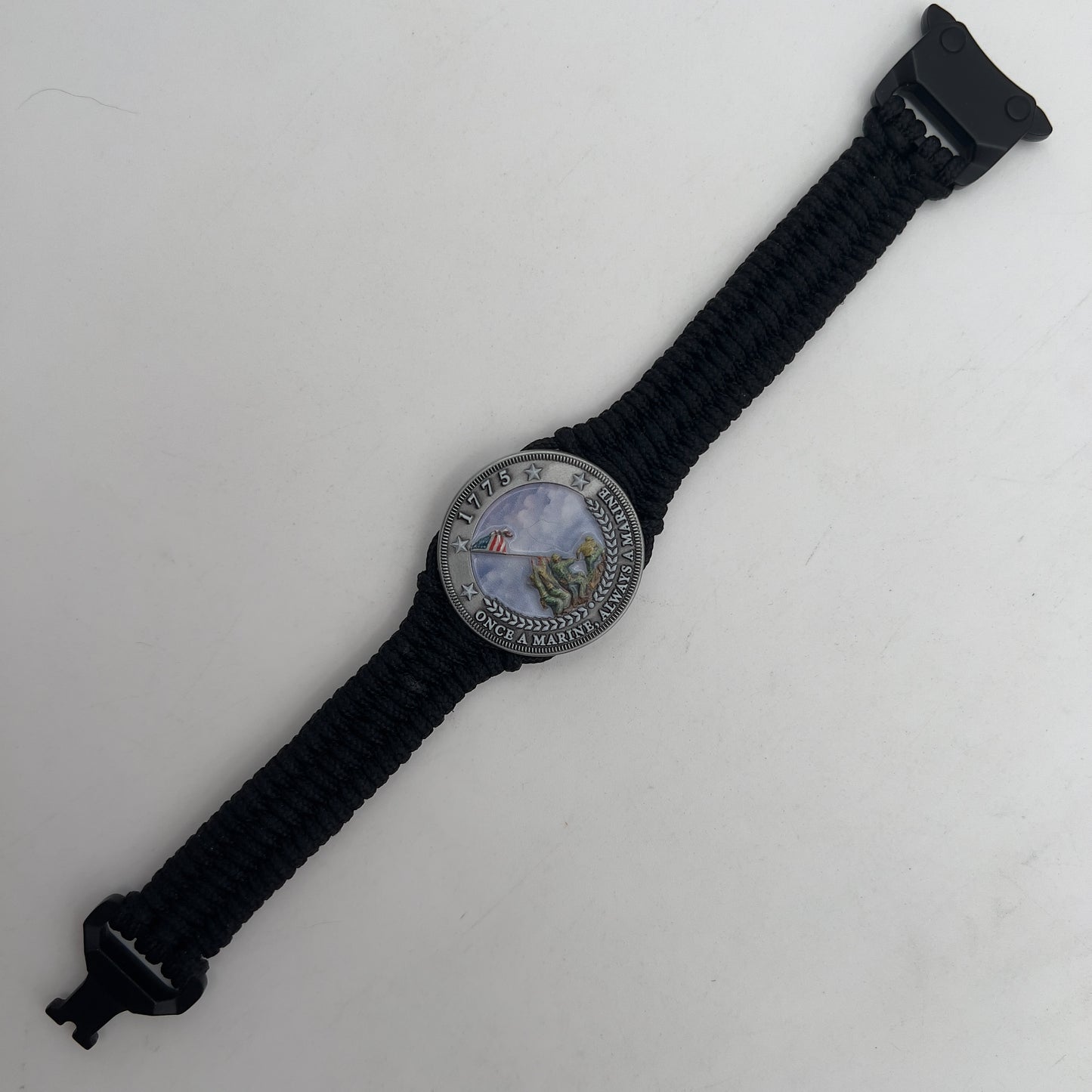 Thin, narrow and comfortable braided United States Marine Corps Iwo Jima bracelet featuring an antique silver plated UV painted Iwo Jima flag raising medallion, a black Cobra style tactical buckle and woven with black type-1 paracord.