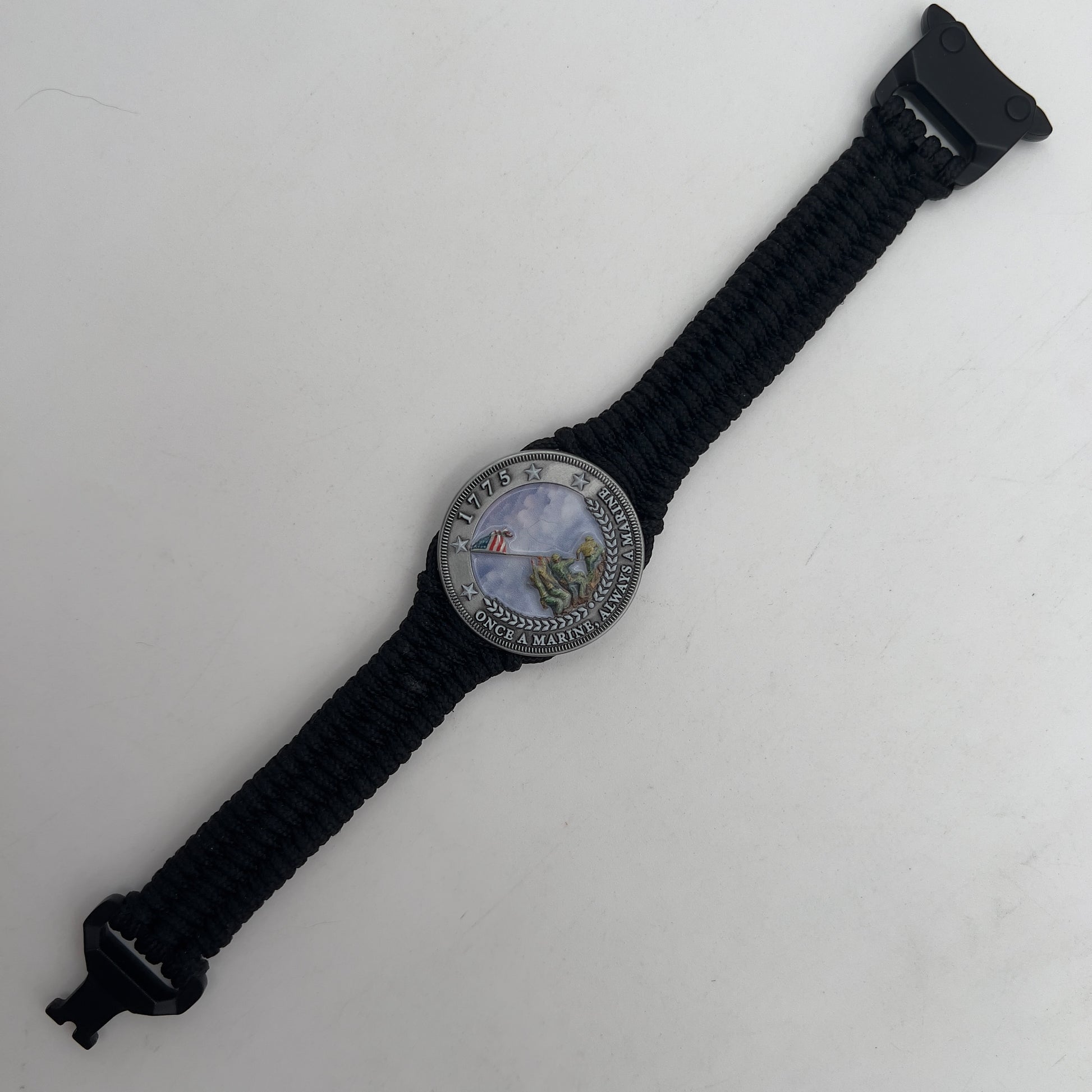 Thin, narrow and comfortable braided United States Marine Corps Iwo Jima bracelet featuring an antique silver plated UV painted Iwo Jima flag raising medallion, a black Cobra style tactical buckle and woven with black type-1 paracord.