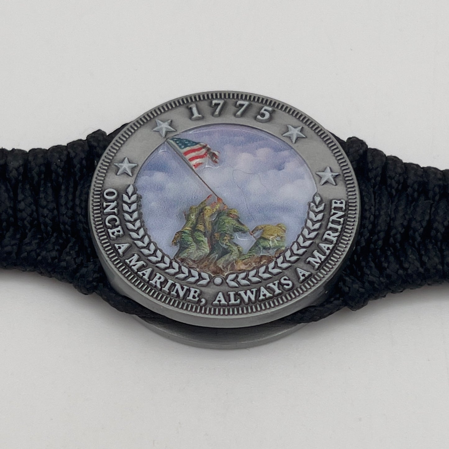 Thin, narrow and comfortable braided United States Marine Corps Iwo Jima bracelet featuring an antique silver plated UV painted Iwo Jima flag raising medallion, a black Cobra style tactical buckle and woven with black type-1 paracord.