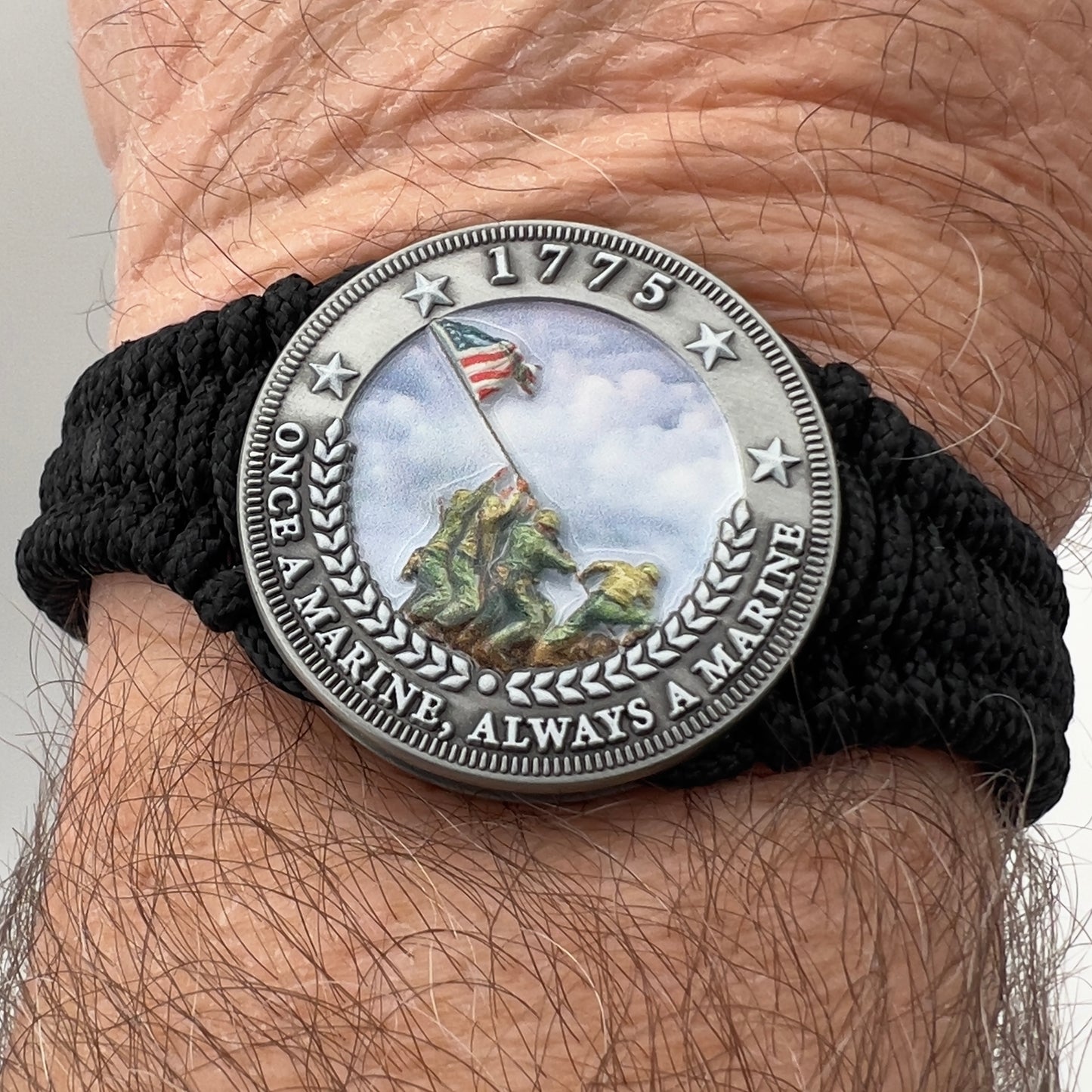 Thin, narrow and comfortable braided United States Marine Corps Iwo Jima bracelet featuring an antique silver plated UV painted Iwo Jima flag raising medallion, a black Cobra style tactical buckle and woven with black type-1 paracord.