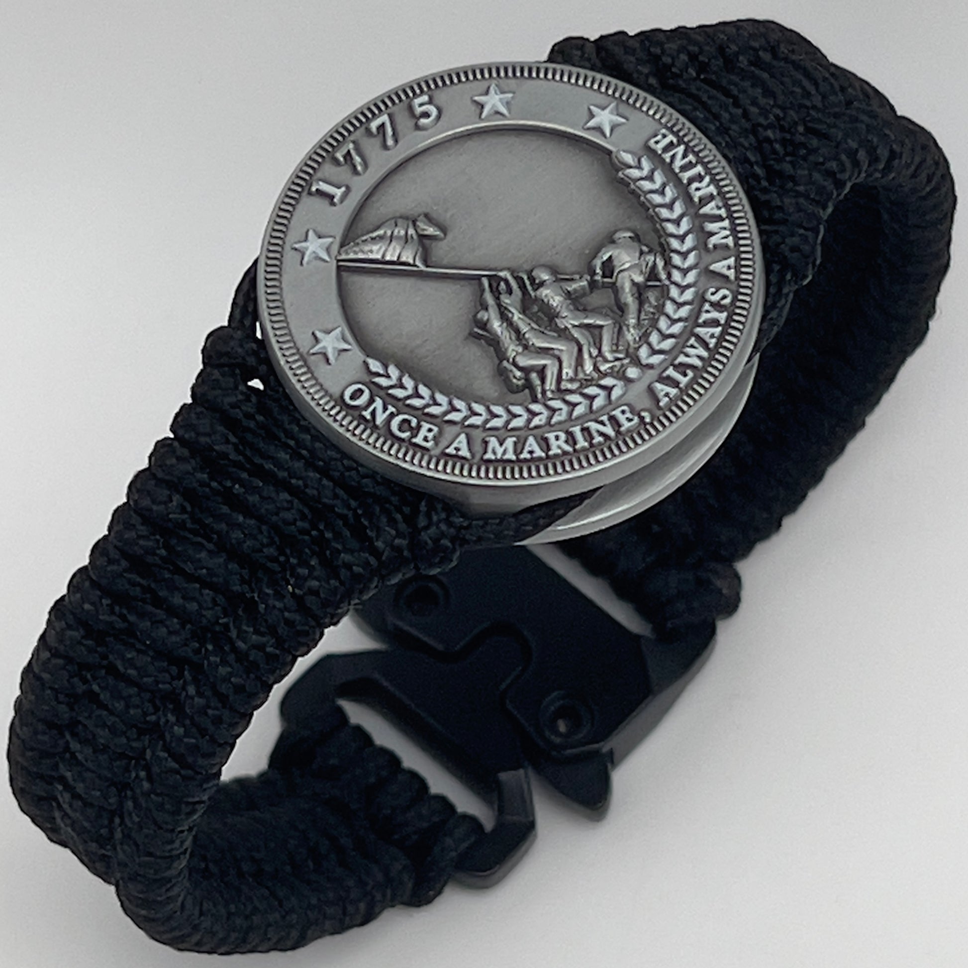 Thin, narrow and comfortable braided United States Marine Corps Iwo Jima bracelet featuring an antique silver plated Iwo Jima flag raising medallion, a black Cobra style tactical buckle and woven with black type-1 paracord.