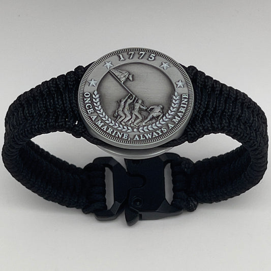 Thin, narrow and comfortable braided United States Marine Corps Iwo Jima bracelet featuring an antique silver plated Iwo Jima flag raising medallion, a black Cobra style tactical buckle and woven with black type-1 paracord.