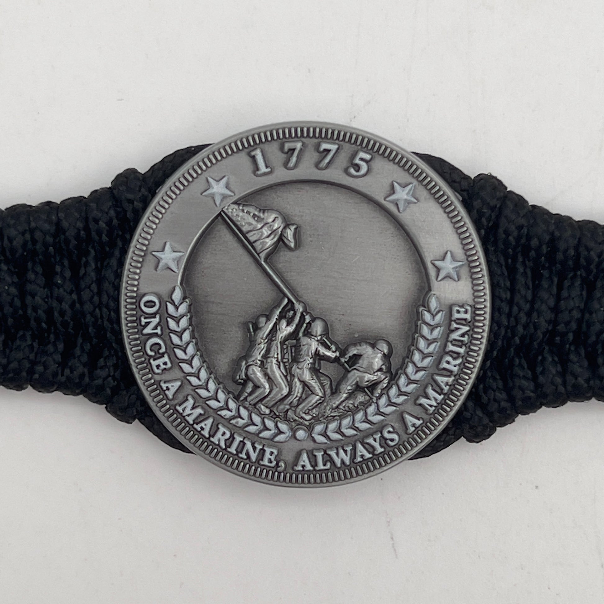 Thin, narrow and comfortable braided United States Marine Corps Iwo Jima bracelet featuring an antique silver plated Iwo Jima flag raising medallion, a black Cobra style tactical buckle and woven with black type-1 paracord.