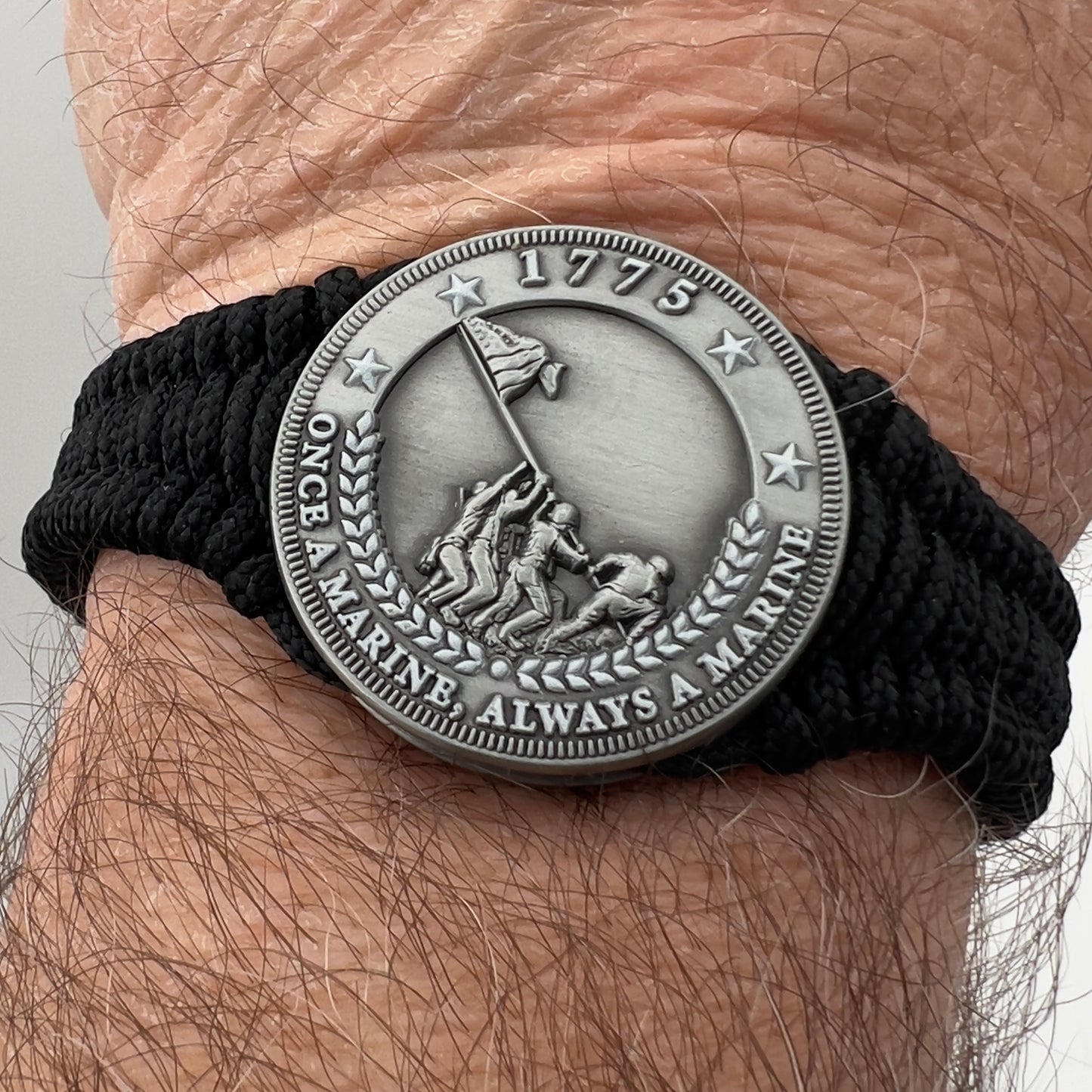 Thin, narrow and comfortable braided United States Marine Corps Iwo Jima bracelet featuring an antique silver plated Iwo Jima flag raising medallion, a black Cobra style tactical buckle and woven with black type-1 paracord.