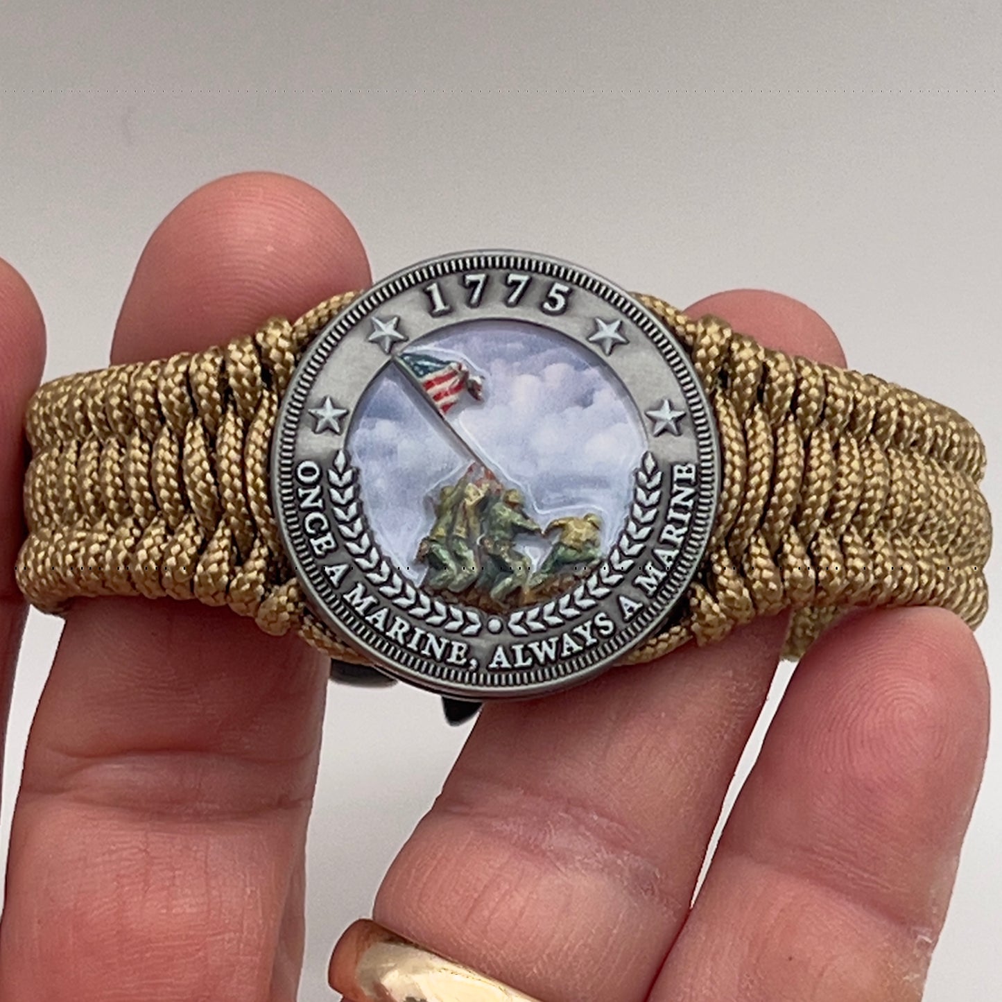 Thin, narrow, flexible and comfortable braided United States Marine Corps Iwo Jima bracelet featuring an antique silver plated UV painted Iwo Jima flag raising medallion, a gold Cobra style tactical buckle and woven with gold type-1 paracord.