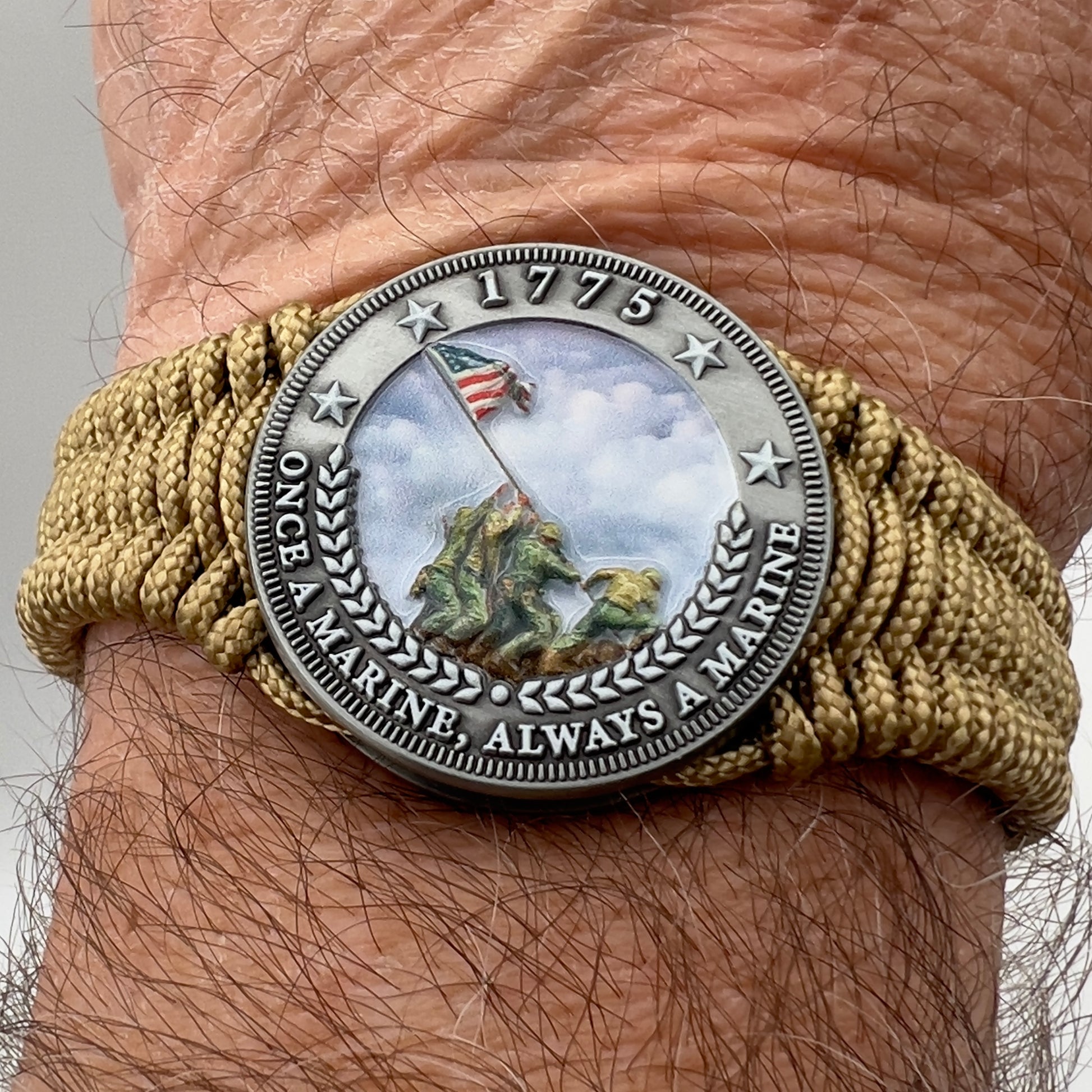 Thin, narrow, flexible and comfortable braided United States Marine Corps Iwo Jima bracelet featuring an antique silver plated UV painted Iwo Jima flag raising medallion, a gold Cobra style tactical buckle and woven with gold type-1 paracord.
