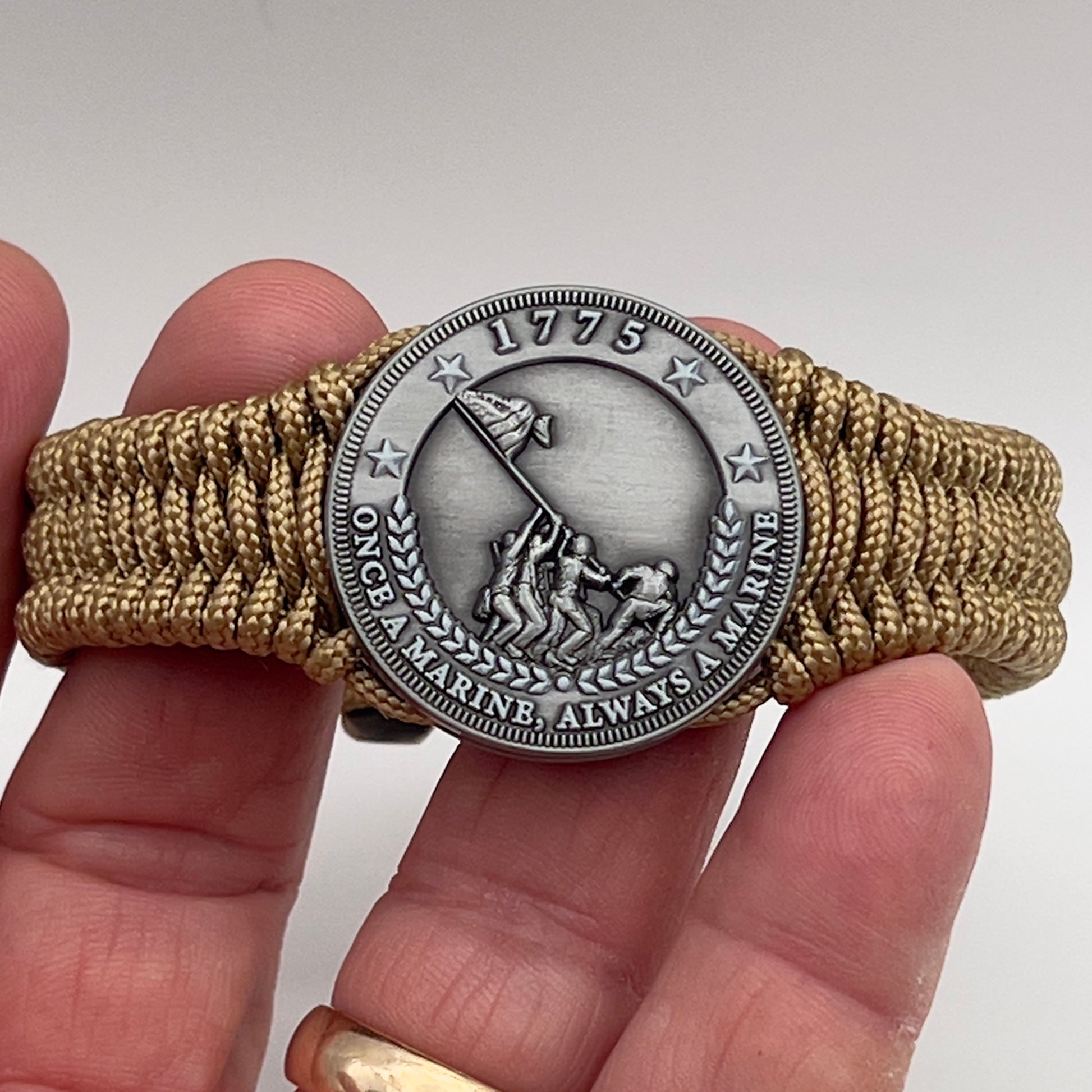 Thin, narrow, flexible and comfortable braided United States Marine Corps Iwo Jima bracelet featuring an antique silver plated Iwo Jima flag raising medallion, a gold Cobra style tactical buckle and woven with gold type-1 paracord.