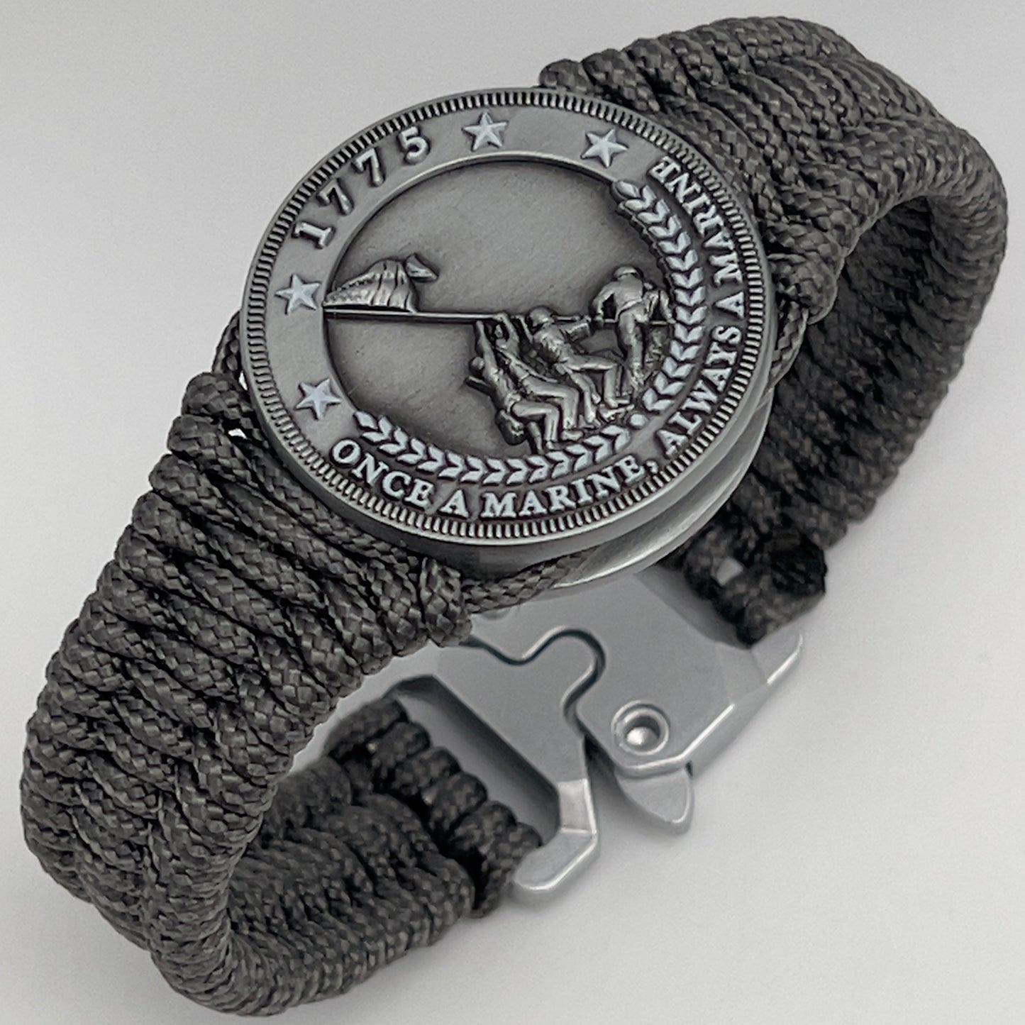 Thin, narrow, flexible and comfortable braided United States Marine Corps Iwo Jima bracelet featuring an antique silver plated Iwo Jima flag raising medallion, a silver Cobra style tactical buckle and woven with Charcoal Gray type-1 paracord.