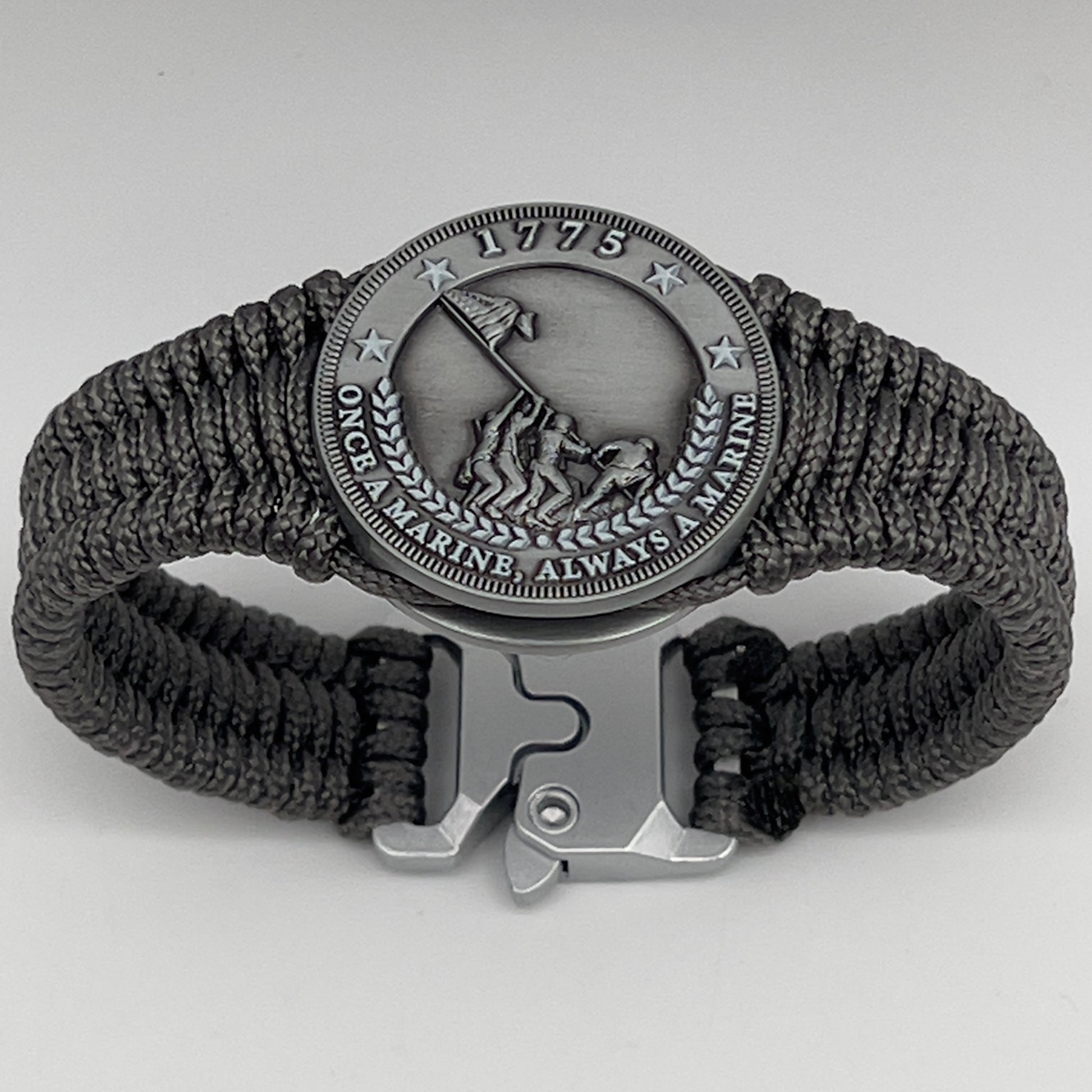 Thin, narrow, flexible and comfortable braided United States Marine Corps Iwo Jima bracelet featuring an antique silver plated Iwo Jima flag raising medallion, a silver Cobra style tactical buckle and woven with Charcoal Gray type-1 paracord.