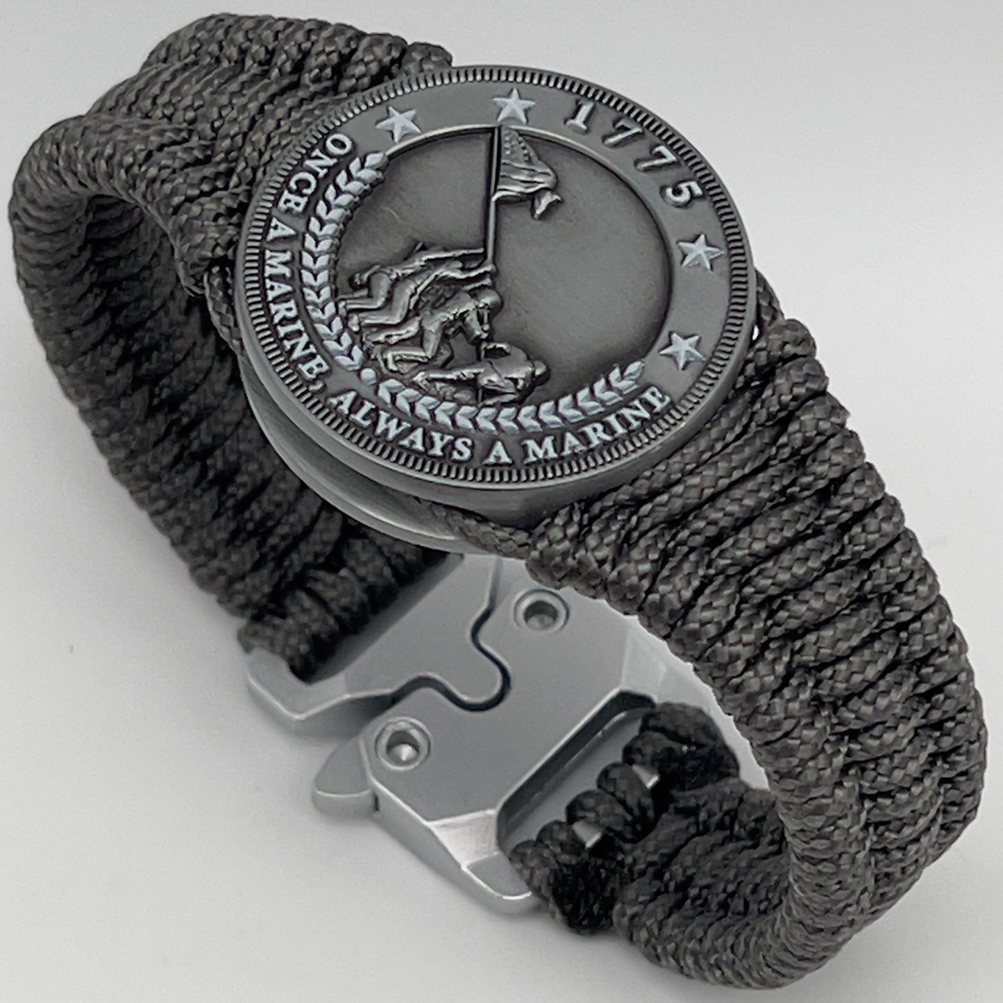 Thin, narrow, flexible and comfortable braided United States Marine Corps Iwo Jima bracelet featuring an antique silver plated Iwo Jima flag raising medallion, a silver Cobra style tactical buckle and woven with Charcoal Gray type-1 paracord.