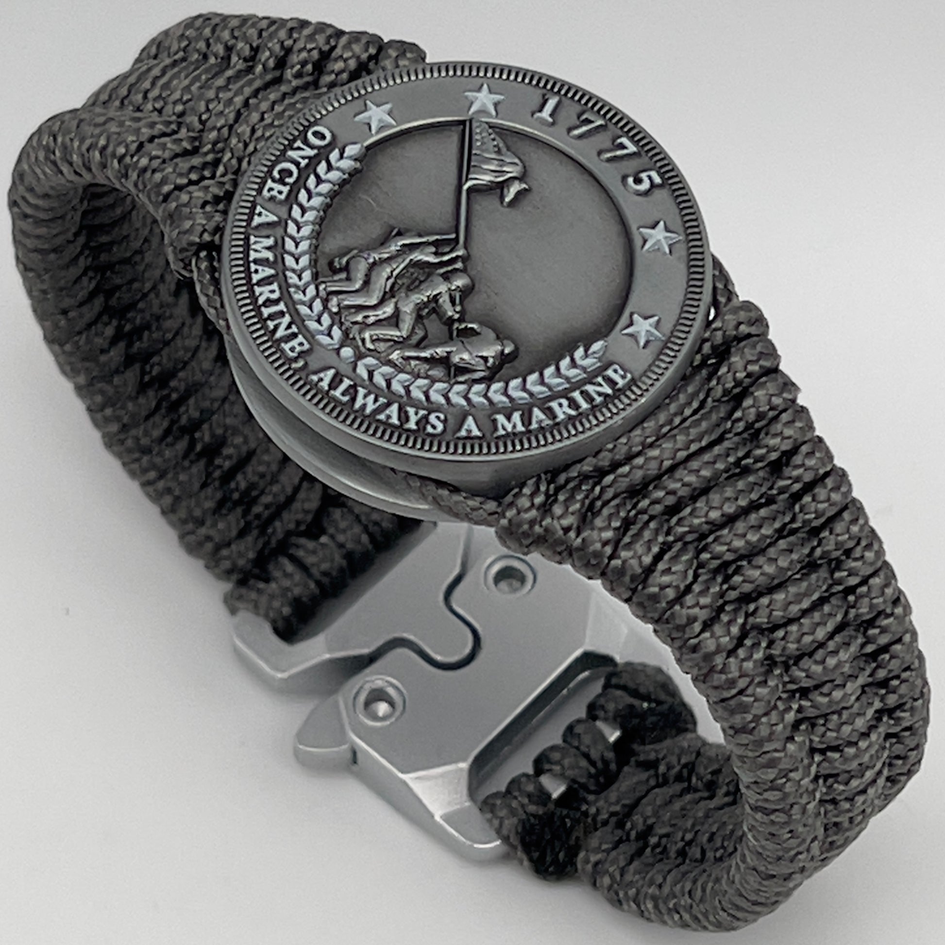 Thin, narrow, flexible and comfortable braided United States Marine Corps Iwo Jima bracelet featuring an antique silver plated Iwo Jima flag raising medallion, a silver Cobra style tactical buckle and woven with Charcoal Gray type-1 paracord.