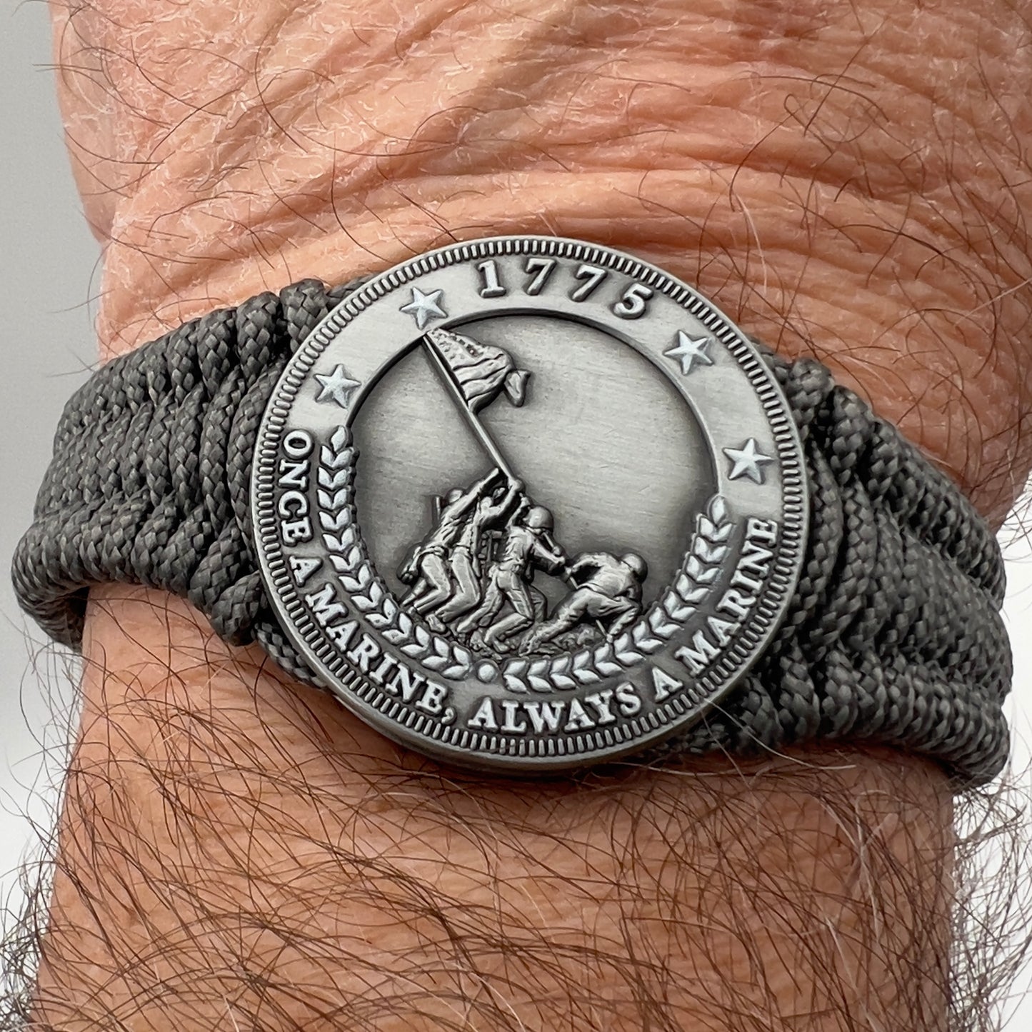 Thin, narrow, flexible and comfortable braided United States Marine Corps Iwo Jima bracelet featuring an antique silver plated Iwo Jima flag raising medallion, a silver Cobra style tactical buckle and woven with Charcoal Gray type-1 paracord.