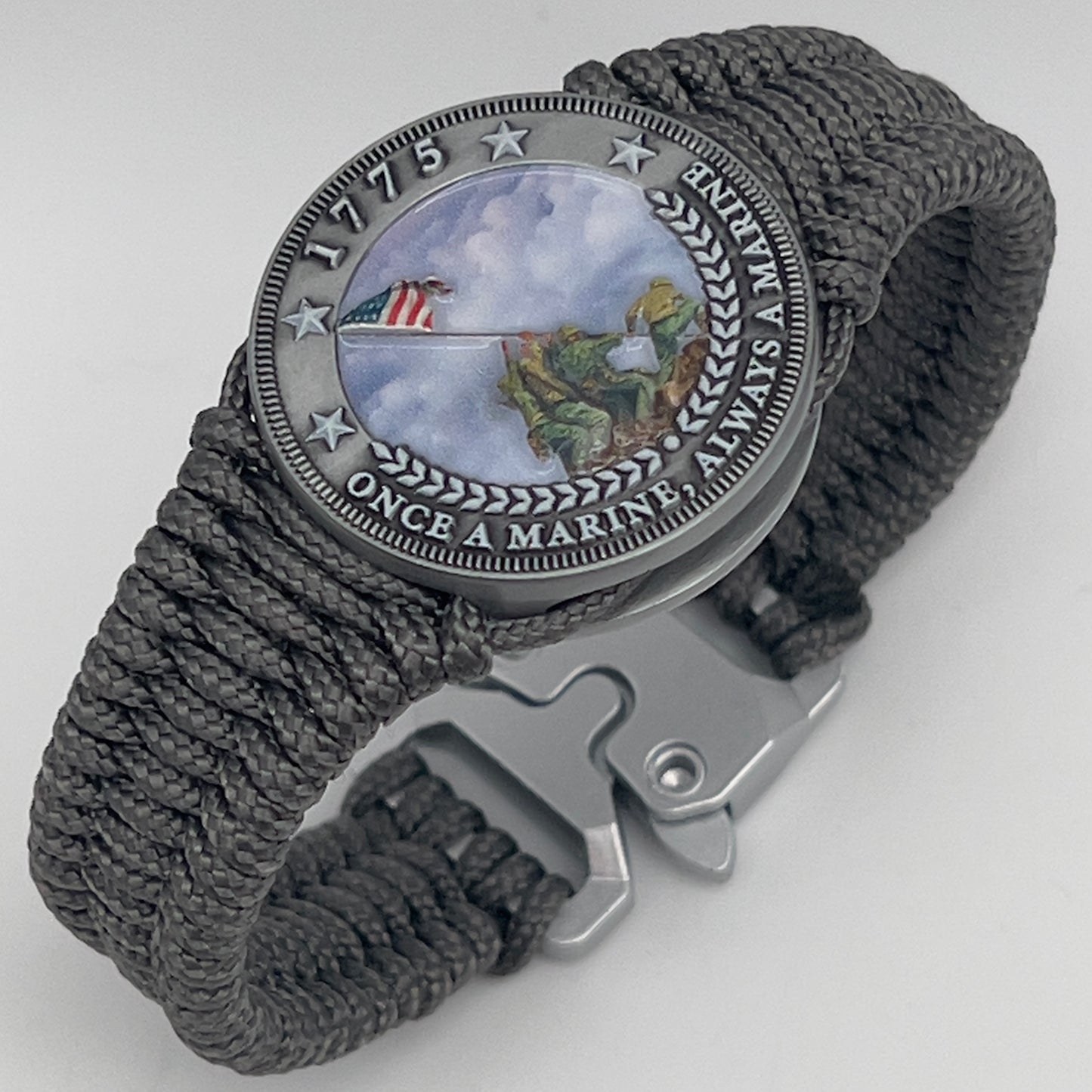 Thin, narrow, flexible and comfortable braided United States Marine Corps Iwo Jima bracelet featuring an antique silver plated UV painted Iwo Jima flag raising medallion, a silver Cobra style tactical buckle and woven with Charcoal Gray type-1 paracord.