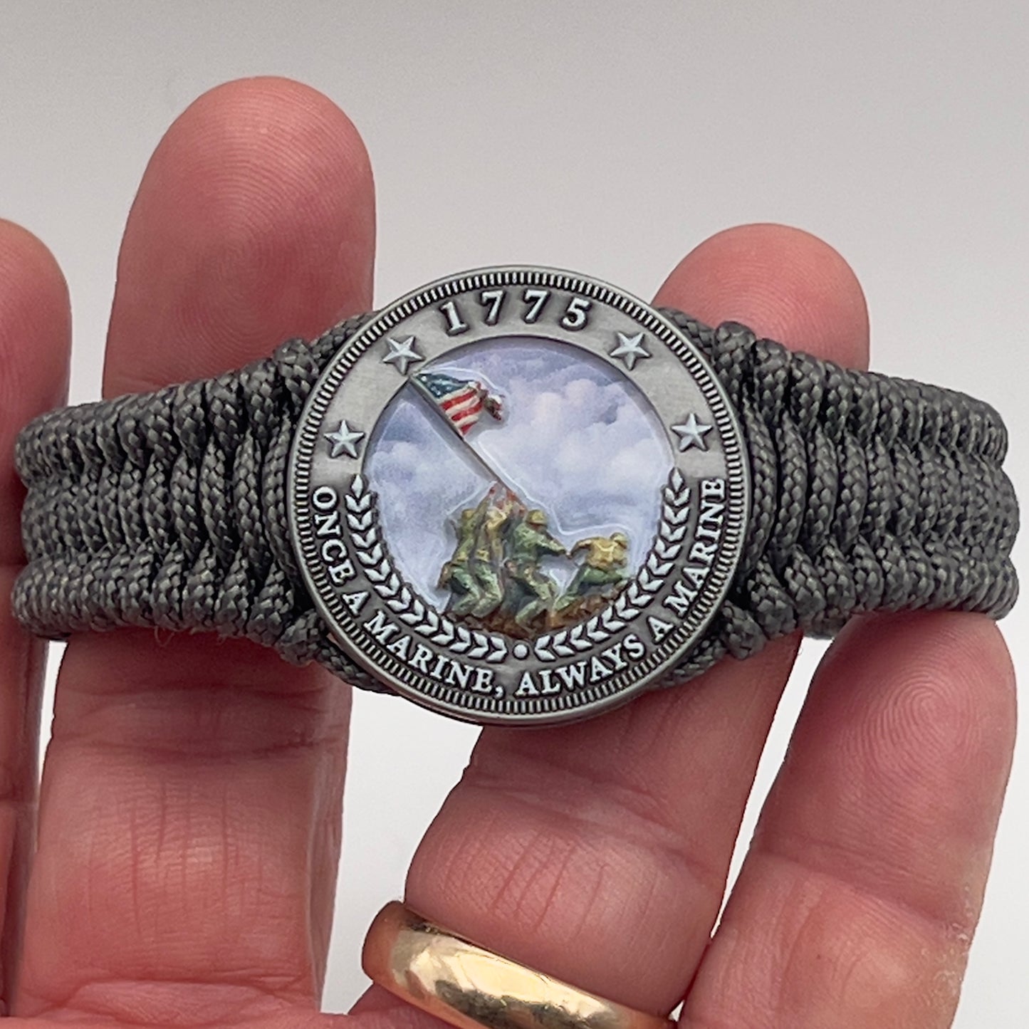 Thin, narrow, flexible and comfortable braided United States Marine Corps Iwo Jima bracelet featuring an antique silver plated UV painted Iwo Jima flag raising medallion, a silver Cobra style tactical buckle and woven with Charcoal Gray type-1 paracord.