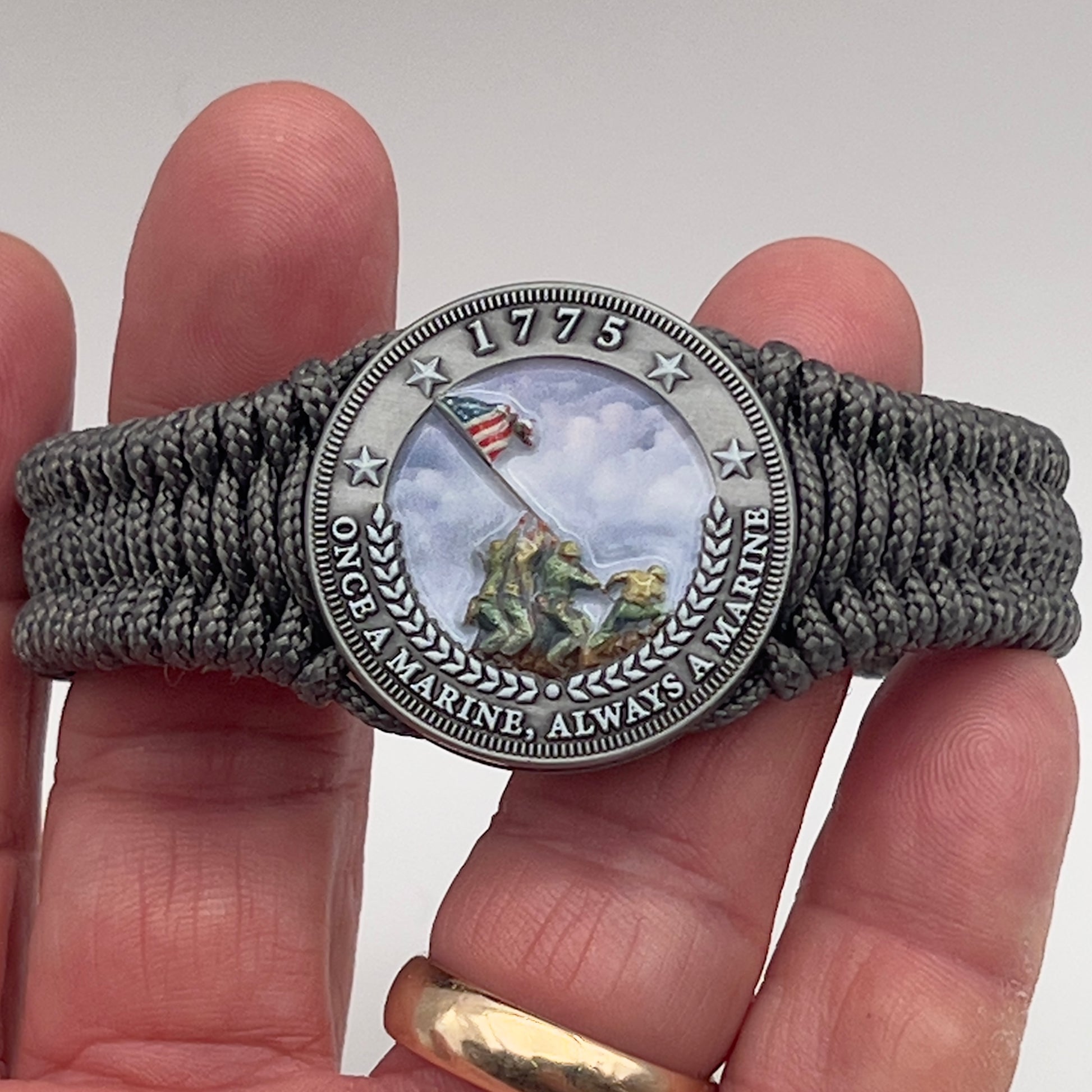 Thin, narrow, flexible and comfortable braided United States Marine Corps Iwo Jima bracelet featuring an antique silver plated UV painted Iwo Jima flag raising medallion, a silver Cobra style tactical buckle and woven with Charcoal Gray type-1 paracord.