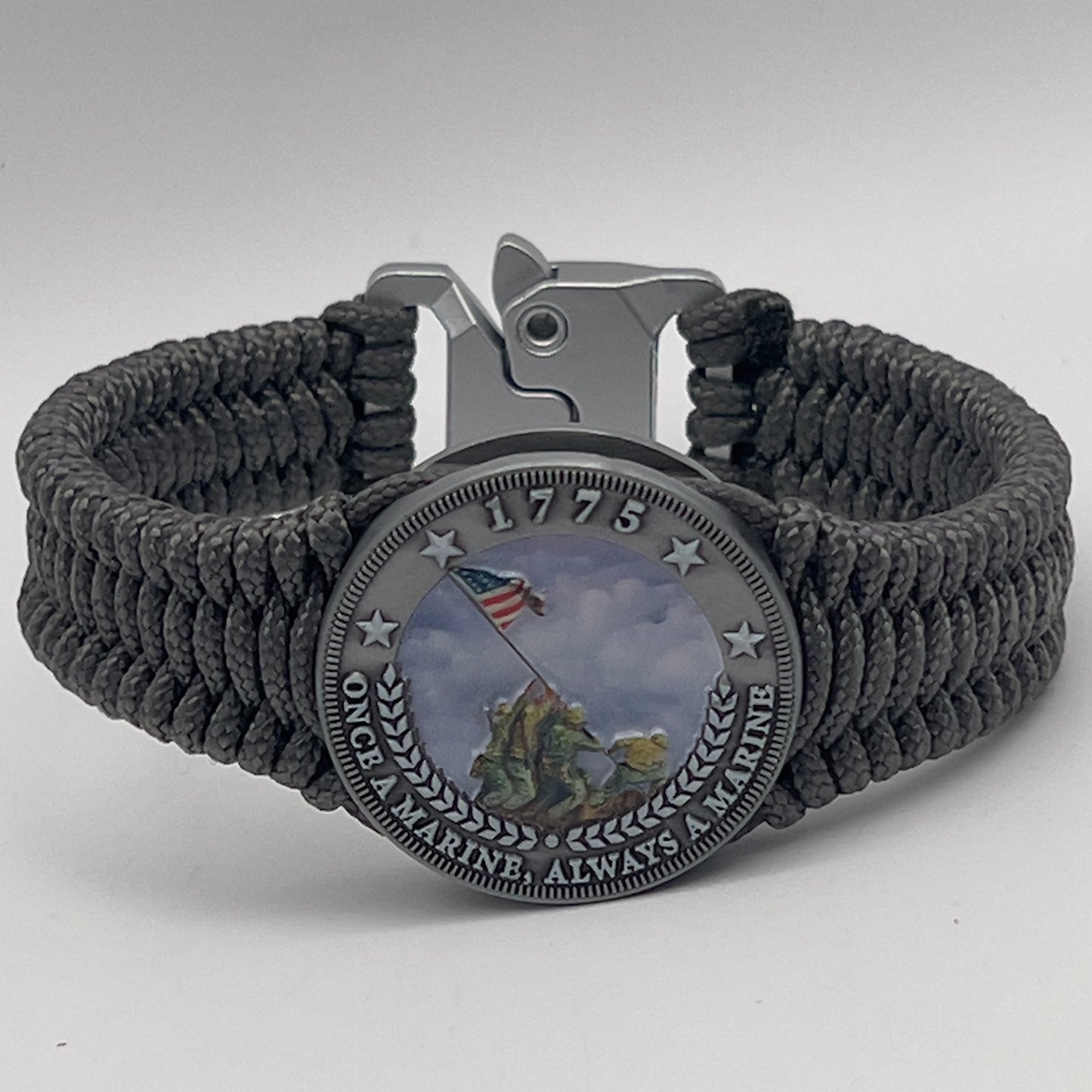 Thin, narrow, flexible and comfortable braided United States Marine Corps Iwo Jima bracelet featuring an antique silver plated UV painted Iwo Jima flag raising medallion, a silver Cobra style tactical buckle and woven with Charcoal Gray type-1 paracord.